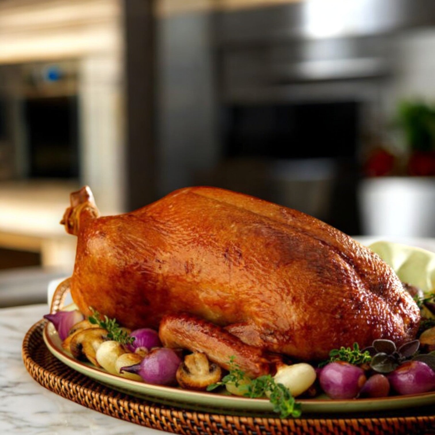 Delight in the view of a Maple Leaf Farms Halal Whole Duck, approximately 5.47 lbs, beautifully surrounded by roasted onions and herbs on a marble countertop in a kitchen setting.