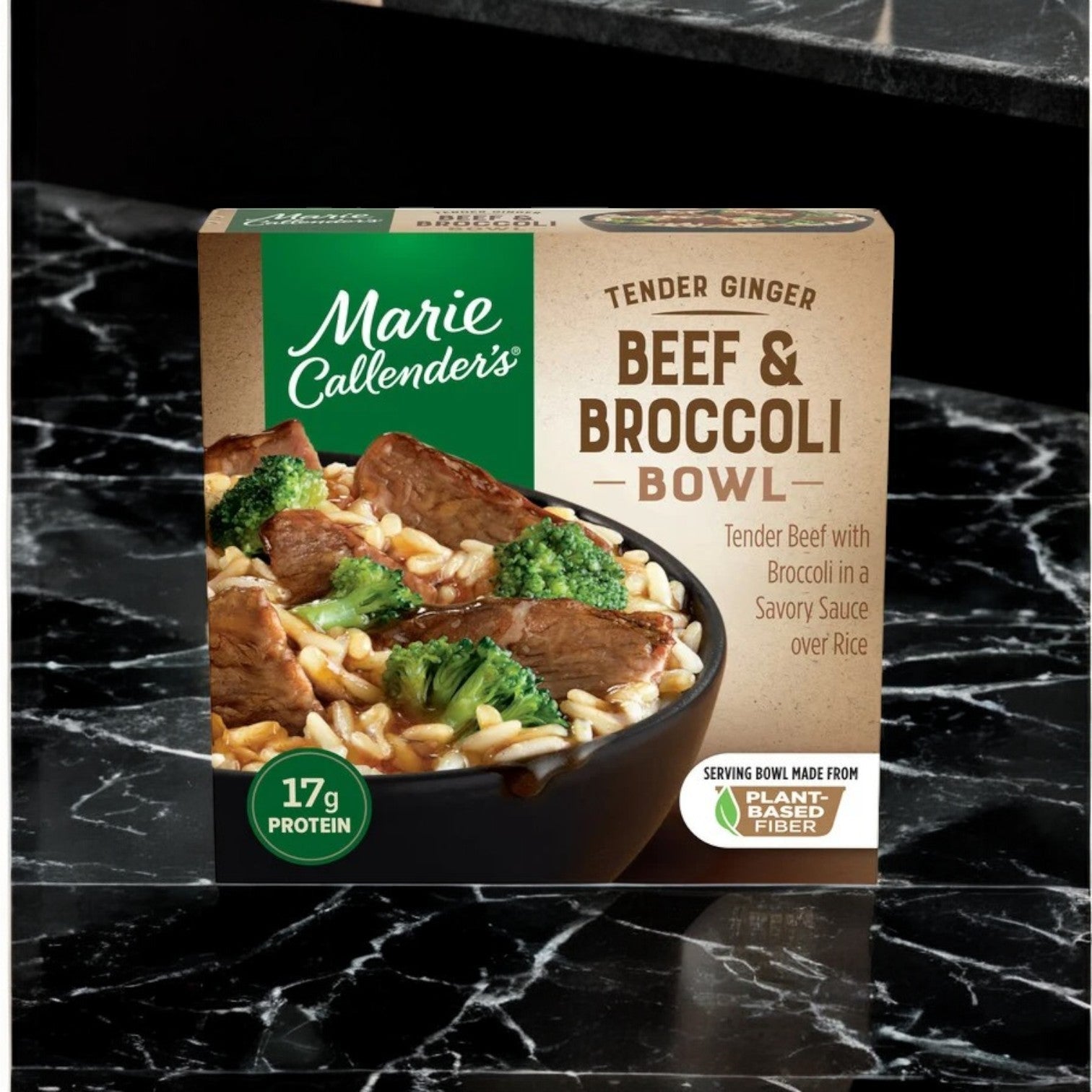 Marie Callender's Beef & Broccoli Bowl, Tender Ginger 11.8 oz., sits on a black marble surface. This meal blends tender beef, broccoli, rice, and savory ginger soy sauce for 17g of protein. The packaging is recyclable.