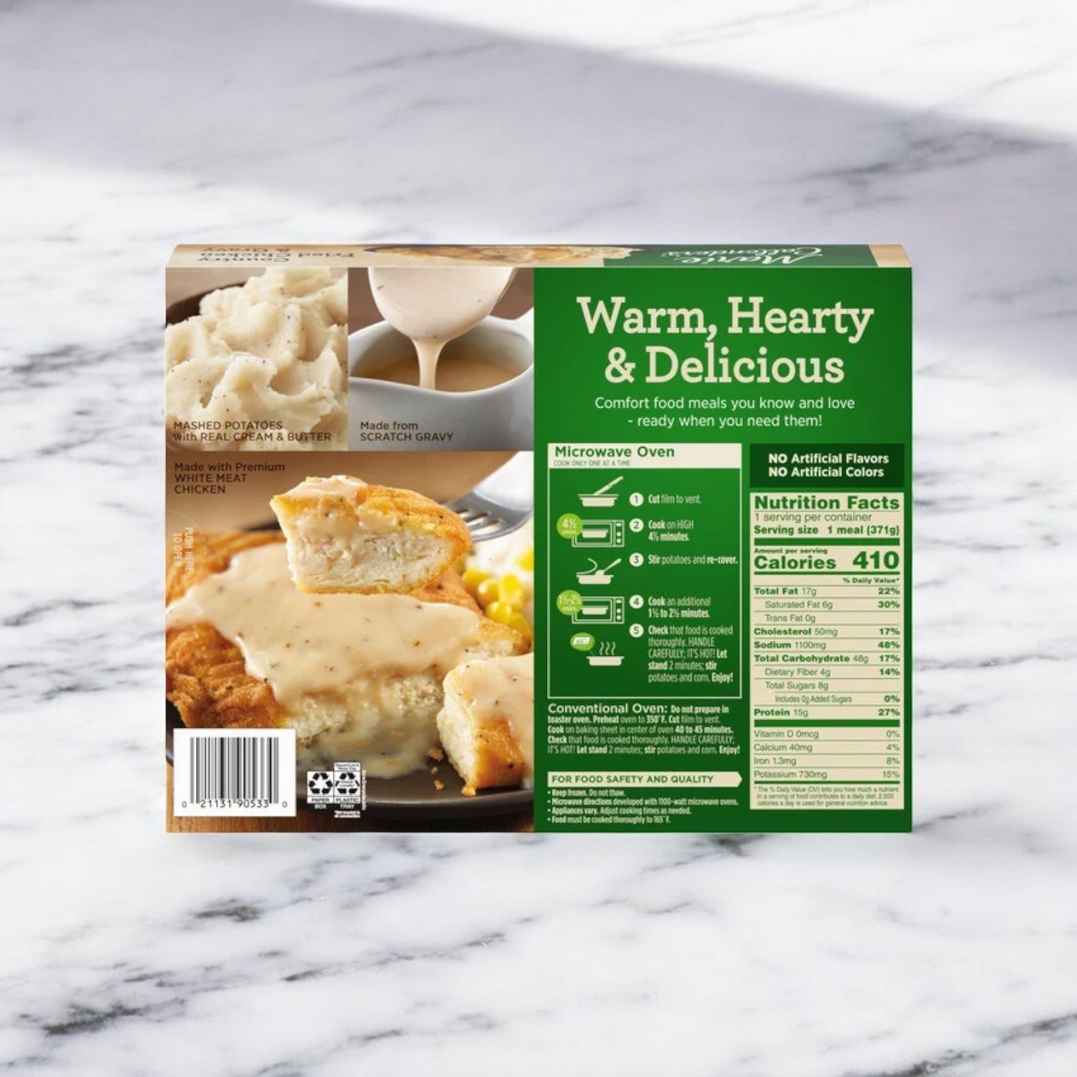 Photograph of the back of a Marie Callender's Country Fried Chicken & Gravy frozen meal package on a marble surface, featuring instructions for heating in a microwave or conventional oven and nutrition facts. The hearty and delicious Southern dish promises to satisfy your cravings.