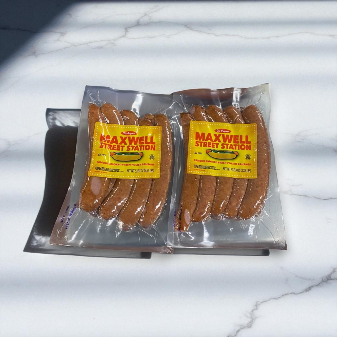 A pack of Vienna Beef Maxwell Street Station Famous Smoked Fresh Polish Sausage, 53.33 oz., sits on a white marble surface with diagonal shadows.