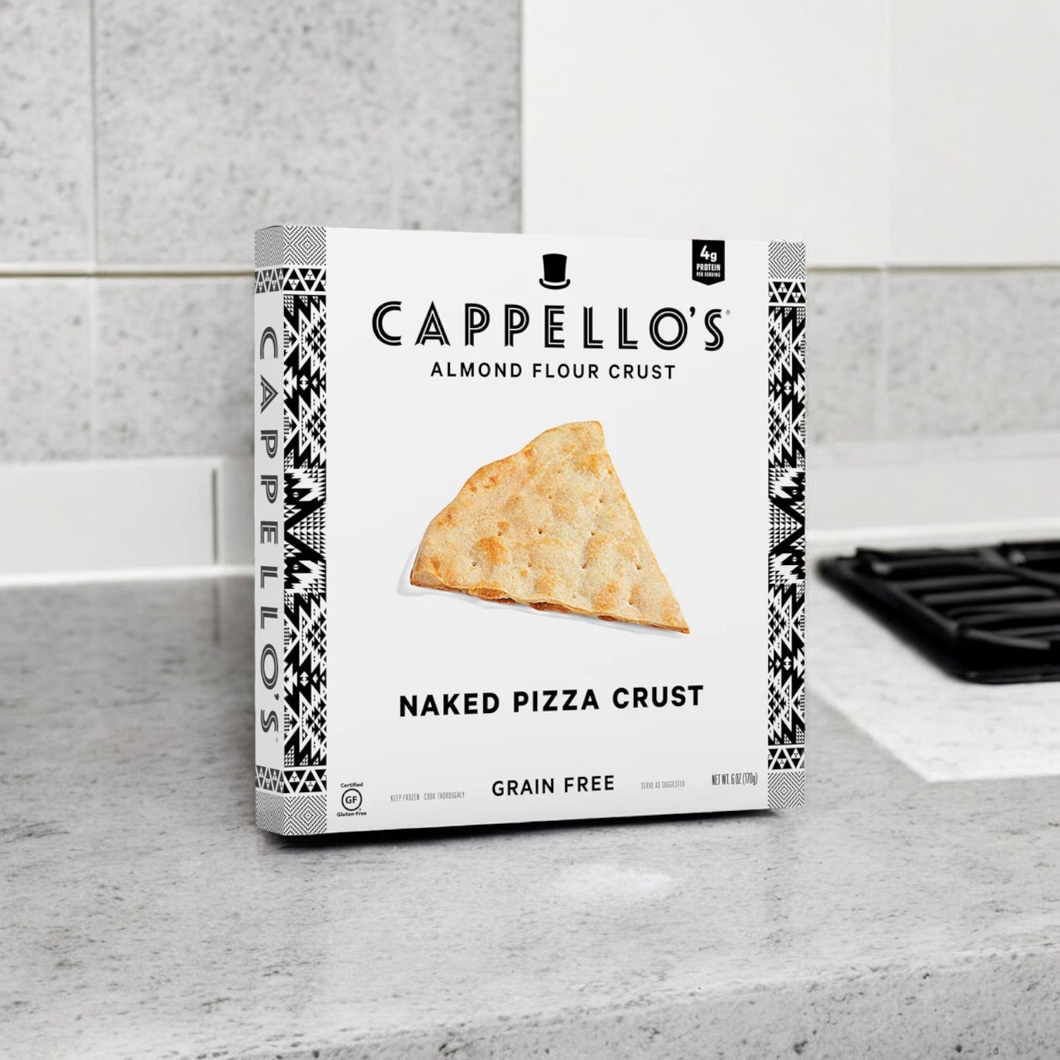 A case of Cappello's Grain Free Naked Pizza Crust, with 6 packs of 6 oz. each, elegantly sits on a gray kitchen countertop next to the stovetop, ready to transform your cooking into a delightful gluten-free pizza experience.