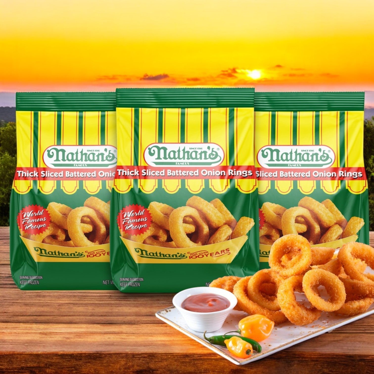 Three 16 oz bags of Nathan’s Famous Onion Rings, Battered, Thick Sliced glisten at sunset outdoors, with a plate of crispy fried rings and tangy dipping sauce enticingly in front.