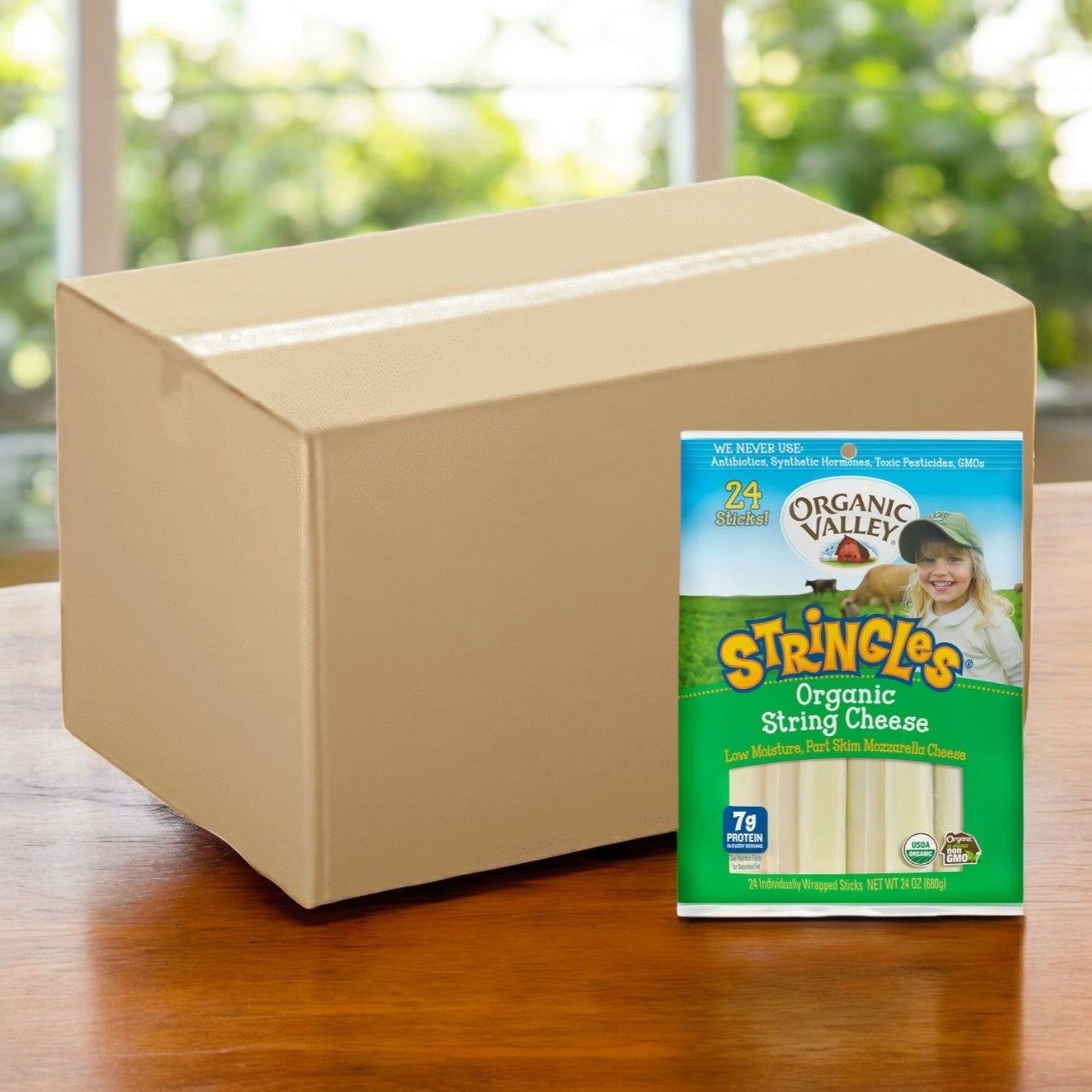 On a wooden table is a case of Organic Valley Stringles Organic String Cheese, containing 5 bags with a total of 120 mozzarella sticks, the ideal healthy snack for your day.