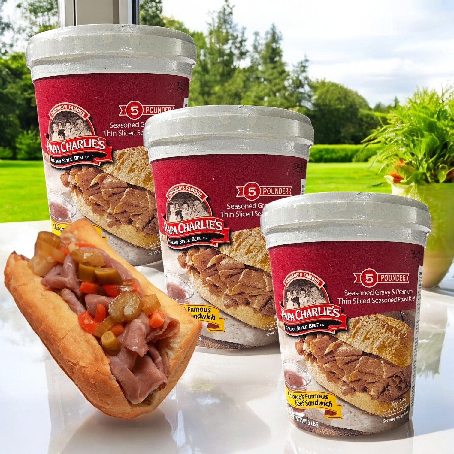 Three containers of Papa Charlie's Thin Sliced Roast Beef (5 pounds each) sit on a wooden surface next to a sandwich filled with roast beef and vegetables.