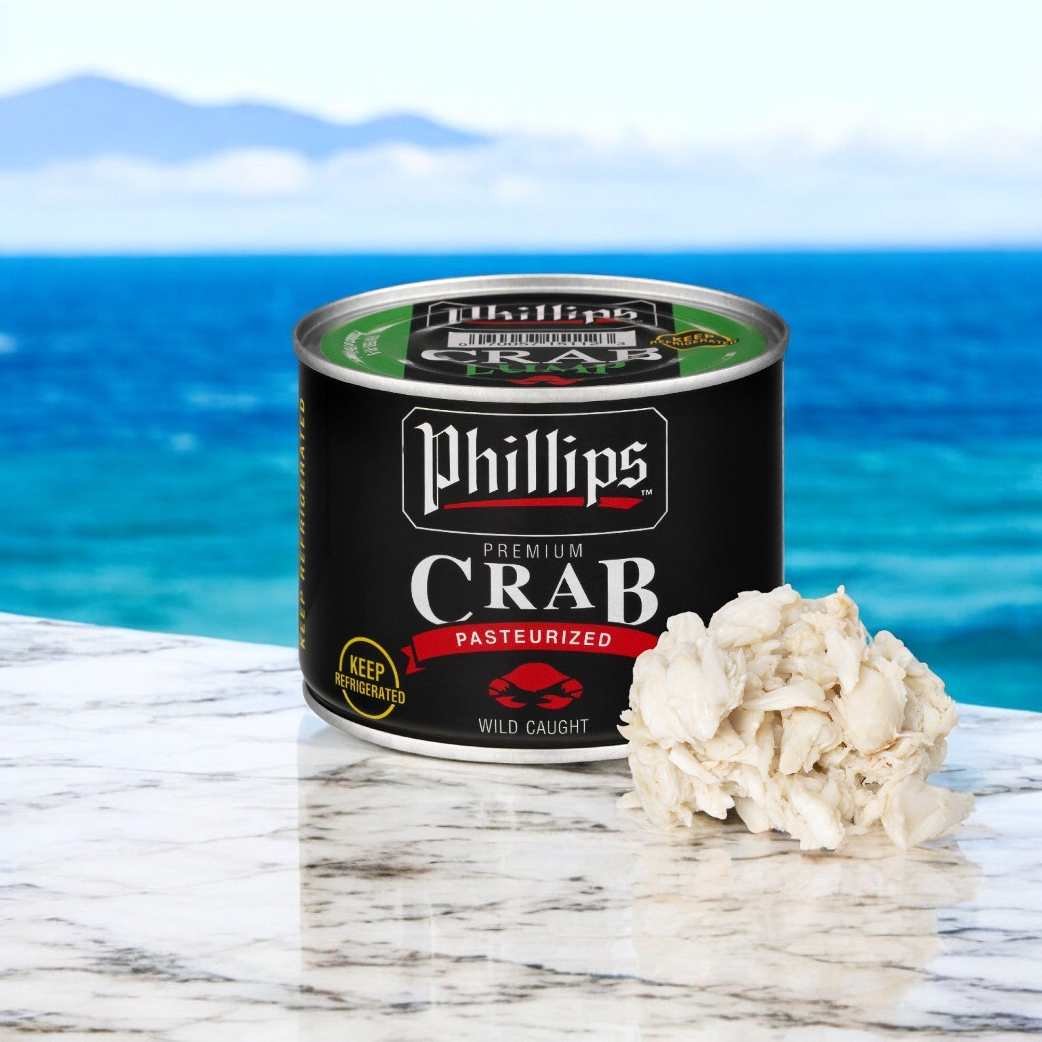 A can of Phillip Foods Crab Meat Lump Pasteurized from Southeast Asia sits on a marble surface next to premium crab meat, with an ocean view as the perfect backdrop.