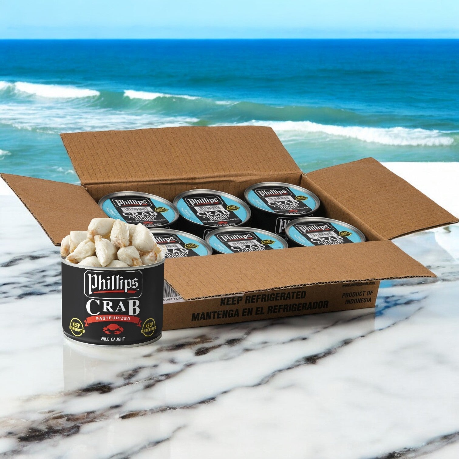 A box of Phillips Foods' Crab Meat Culinary Jumbo Pasteurized Asia Cans sits elegantly on a marble surface, with an ocean view providing a serene backdrop. Perfect for creating exquisite seafood dishes that capture the essence of the sea. Includes 6 cans totaling 6 pounds.