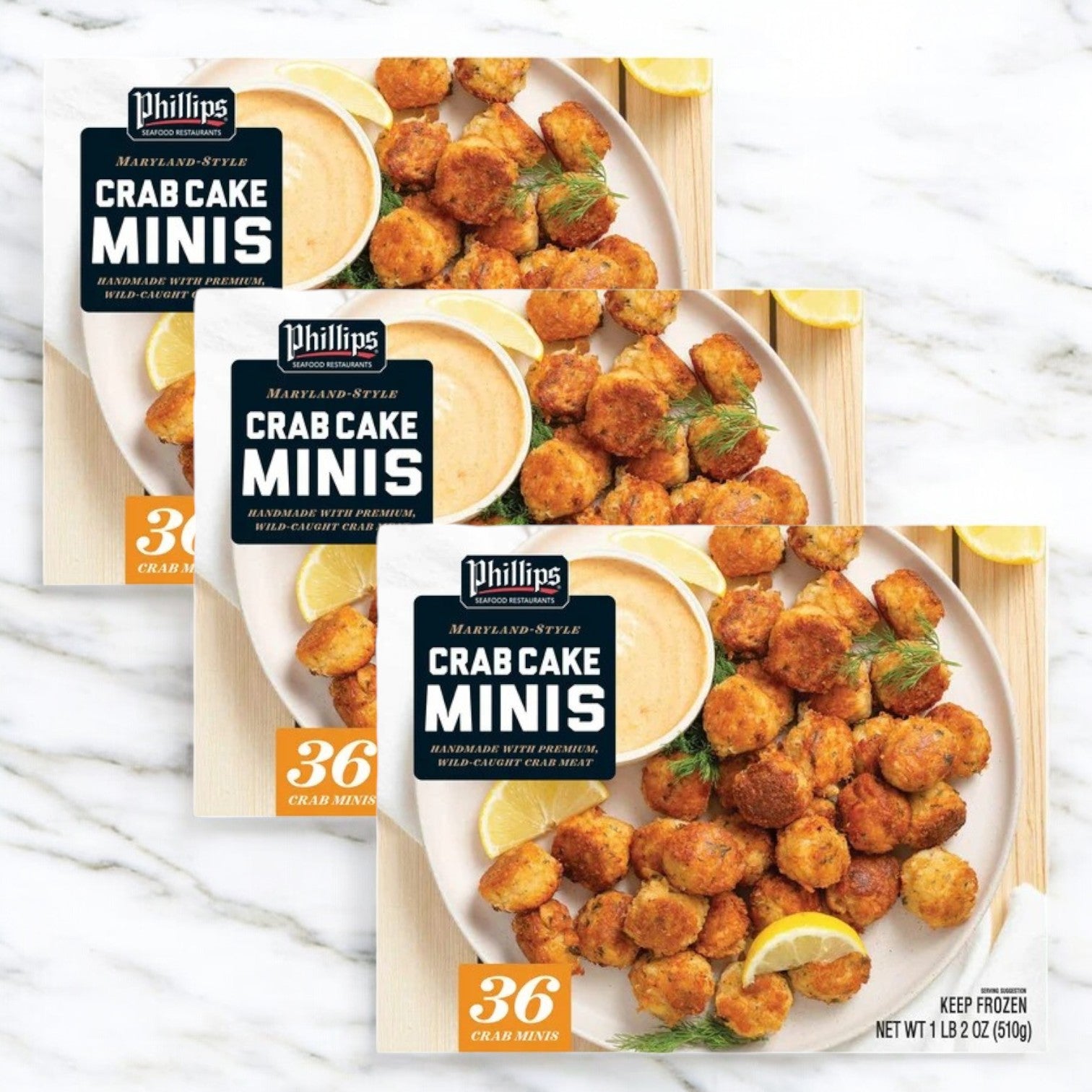 Three packages of Phillips Crab Cake Minis, each containing 36 premium minis by Phillips Foods, are neatly stacked on a marble surface, elegantly garnished with dill and lemon for freshness.