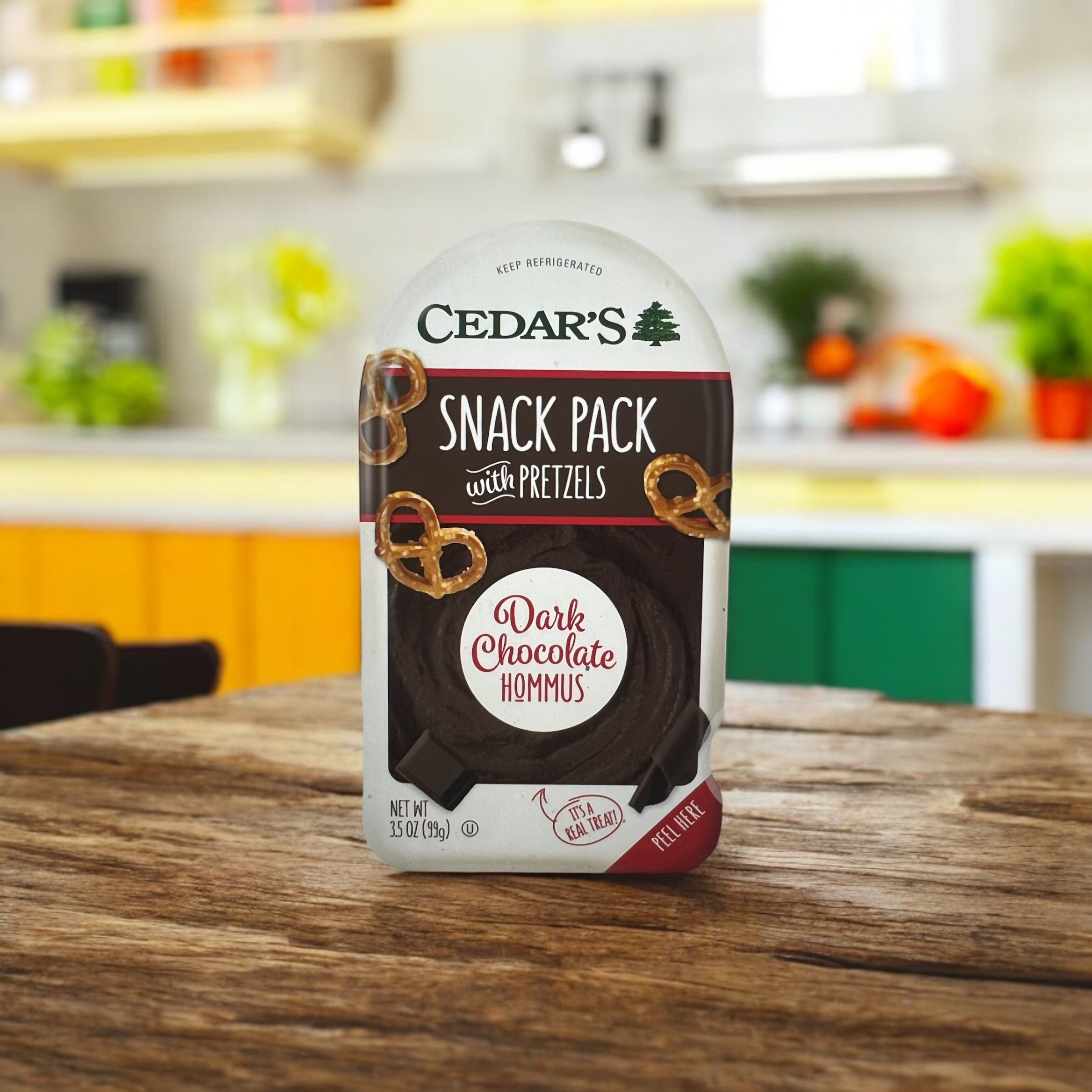 A Cedar's Snack Pretzels with Chocolate Hommus - 1 Count pack sits on a wooden table in a kitchen.