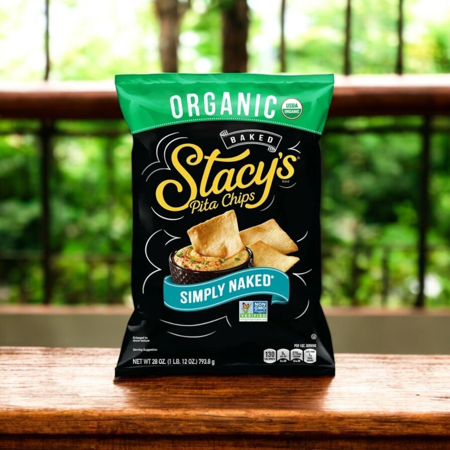 The Pita Inn Hummus & Stacy’s Pita Chips Combo – The Perfect Pair!! sits elegantly on a wooden surface, with its wholesome Mediterranean crunch enhanced by blurred green foliage, delivering an authentic flavor experience.