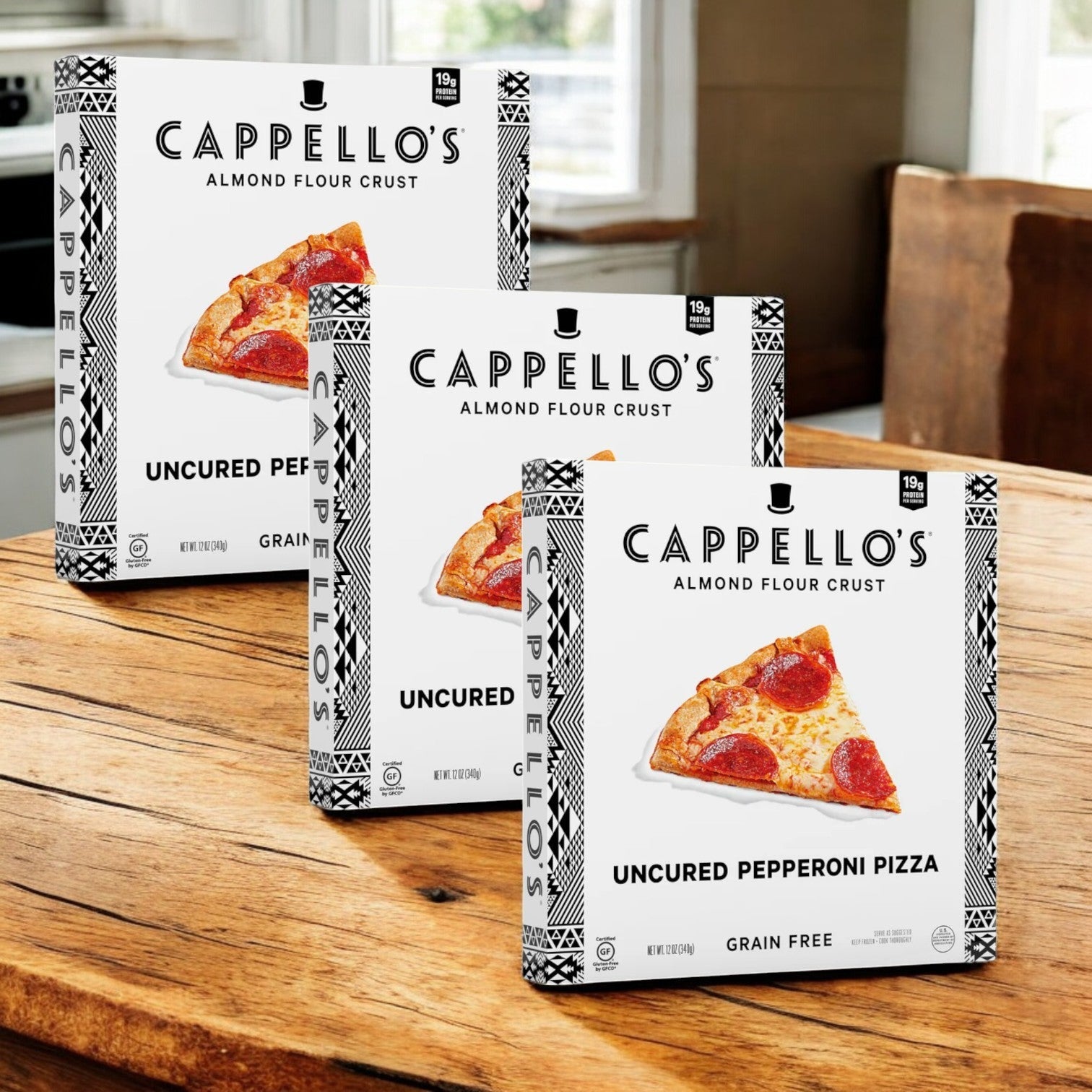 Three boxes of Cappello's Uncured Pepperoni Pizza, 12 oz-3 Count, featuring an almond flour crust and handcrafted with quality ingredients, are displayed on a kitchen counter.