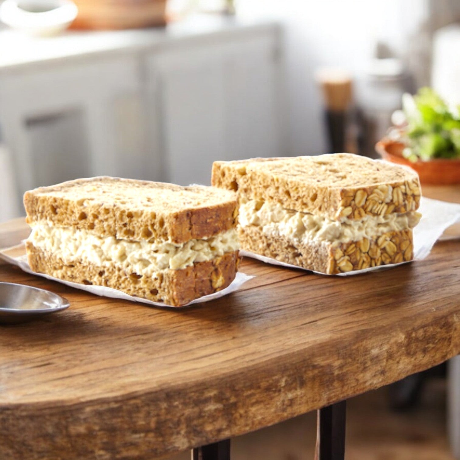The E.A. Sween Albacore Tuna Salad Sandwich, featuring oat bread and a 30-day shelf life once thawed, brings a fresh twist to classic flavors while sitting perfectly on any wooden table.