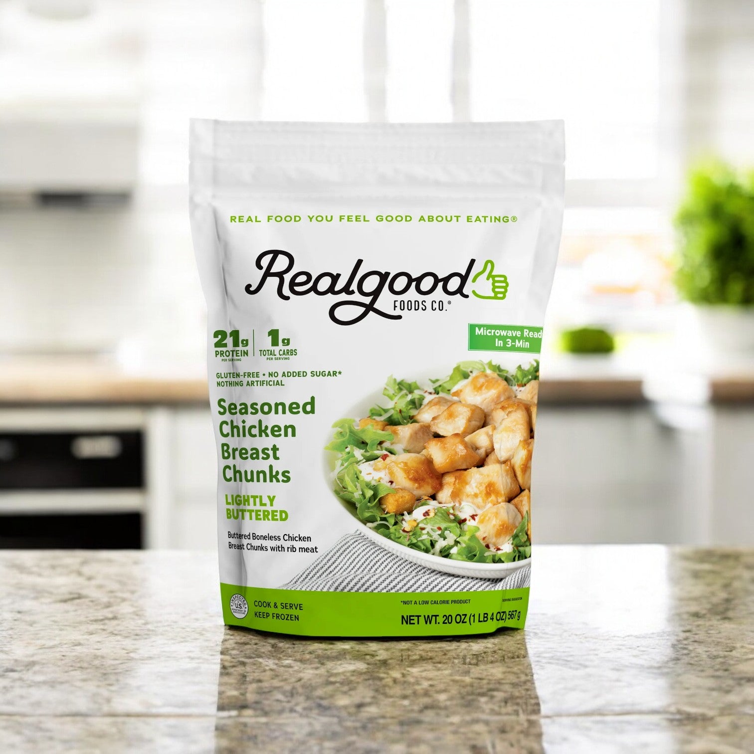 A 20 oz bag of Real Good Foods Lightly Buttered Chicken Breast Nuggets is on the kitchen counter, featuring 23g of protein and no added sugar.
