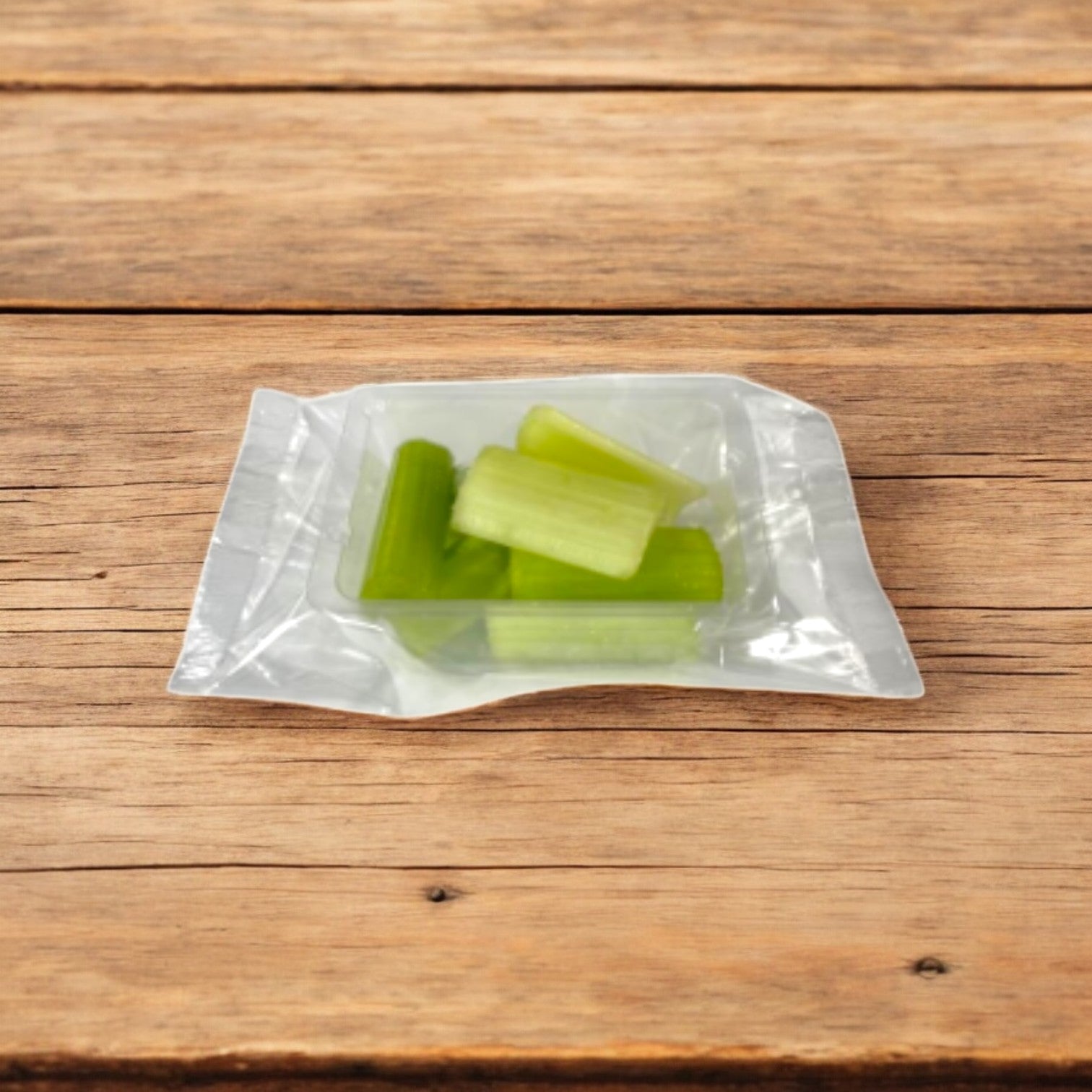 A sealed plastic package from Easy Lunches, containing fresh, chopped Celery Sticks (2.5 oz. - 100 Pack), sits on a wooden surface—a crisp and nutritious snack with a 7-day shelf life upon delivery.