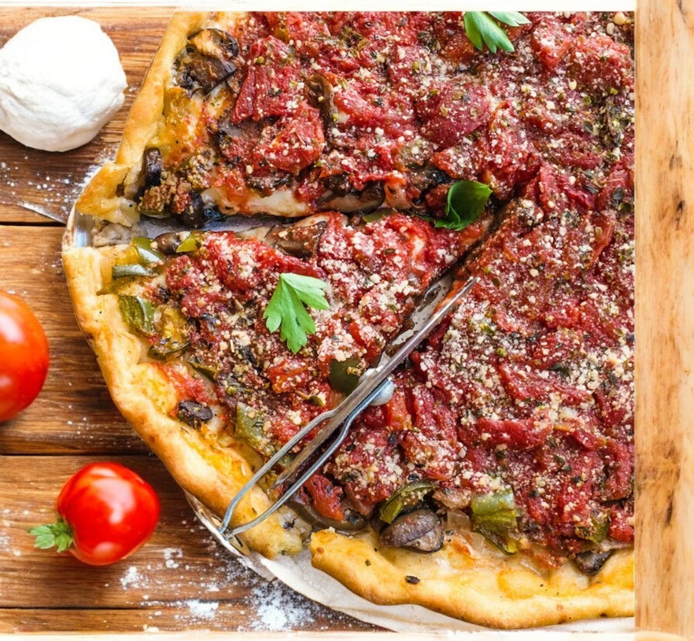 My Pi Pizza Sausage, Mushroom, Onion, and Green Pepper Deep Dish Pizza features savory tomato sauce and cheese topped with parsley. Displayed on a wooden surface with cherry tomatoes and mozzarella nearby, this My Pi Pizza offering promises a mouthwatering experience.