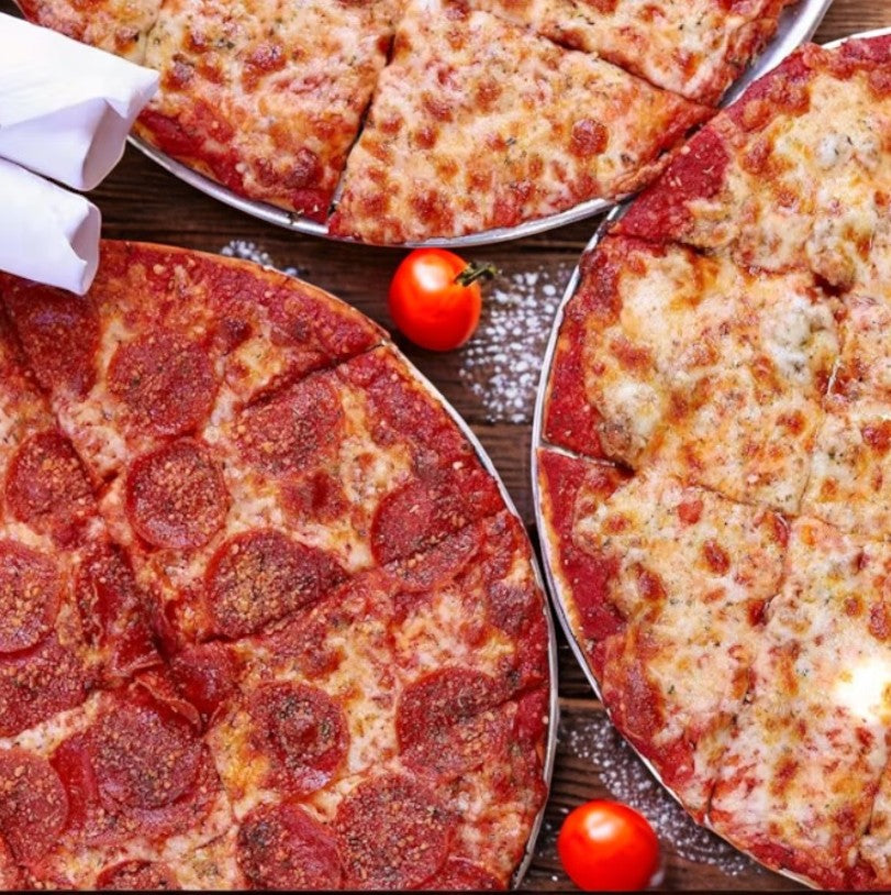 Three Labriola Chicago Thin Crust pizzas—a cheese, a pepperoni, and a sausage—are on plates on a wooden table with scattered cherry tomatoes and a folded napkin. This Labriola Pizza 3 Count Combo offers the perfect variety.