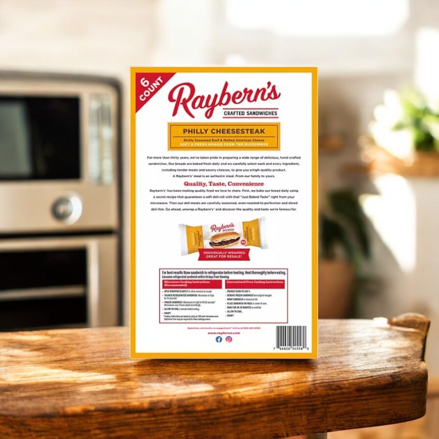 A pack of Raybern's Philly Cheesesteak Crafted Sandwiches sits on a kitchen counter near an oven, bathed in natural light, promising a protein-packed treat for any meal.