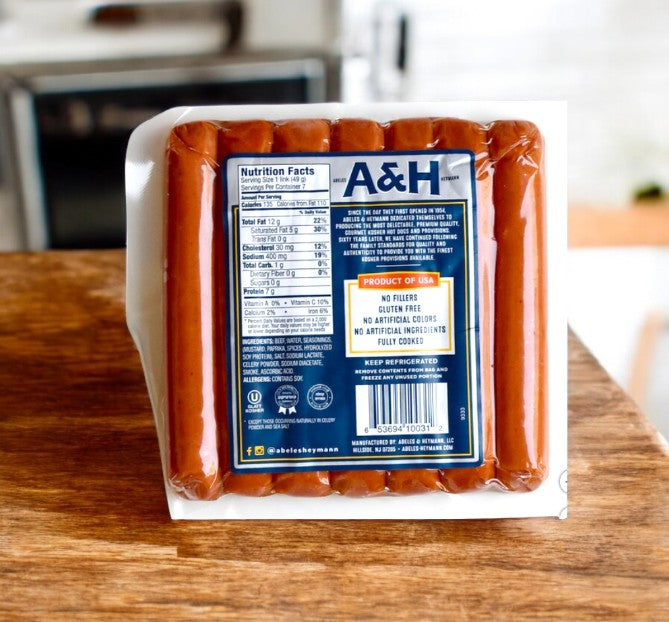 A package of A&H Meats' A & H All Beef Kosher Hot Dogs, 12Oz-1 Pack, sits on a wooden surface with nutrition facts and product details clearly visible. These certified kosher hot dogs ensure quality and flavor in every bite, perfect for any gathering.