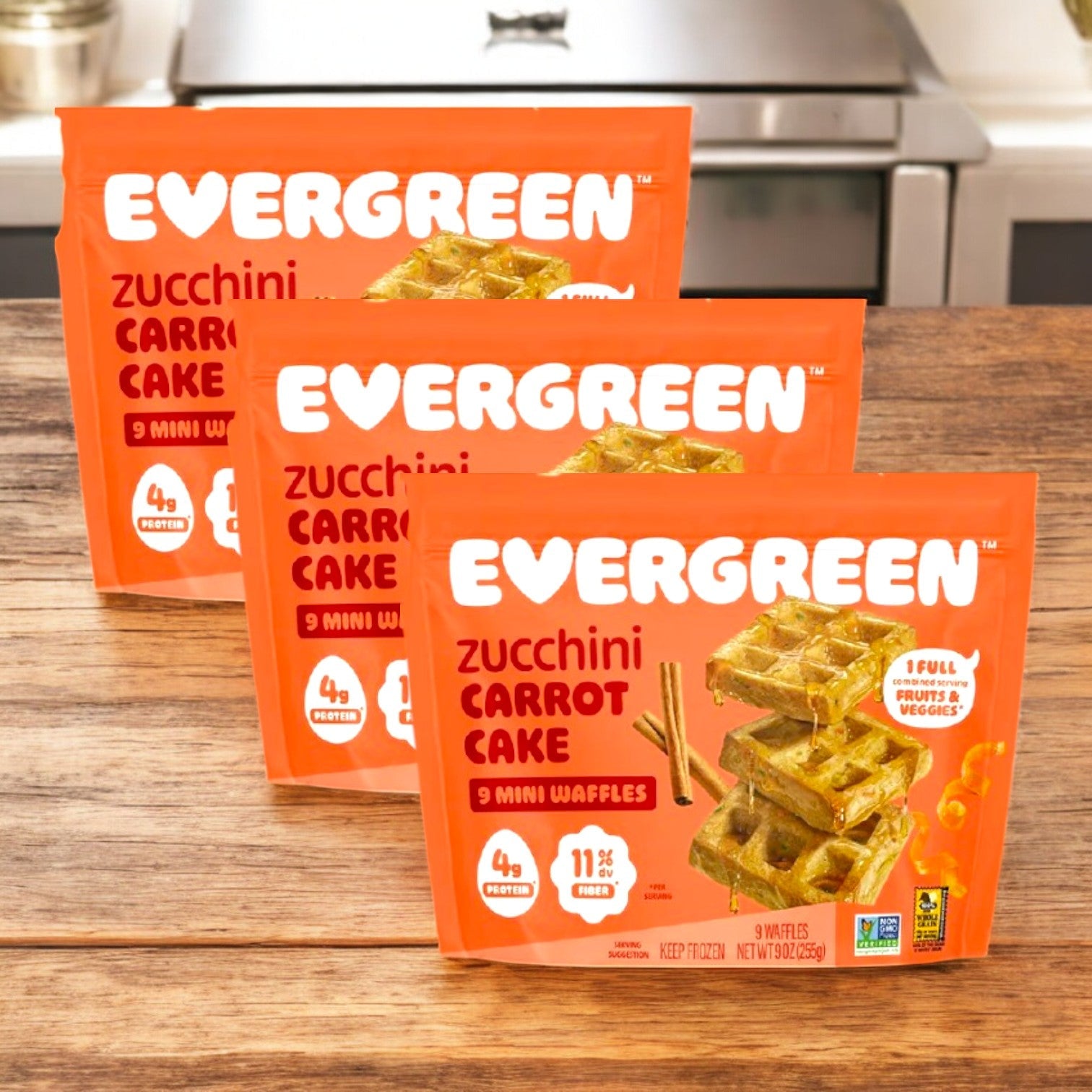 Evergreen Zucchini Carrot Cake Frozen Mini Waffles, 9 oz. - 3 Count, are displayed on a wooden counter in a kitchen—perfect for a nutritious breakfast.