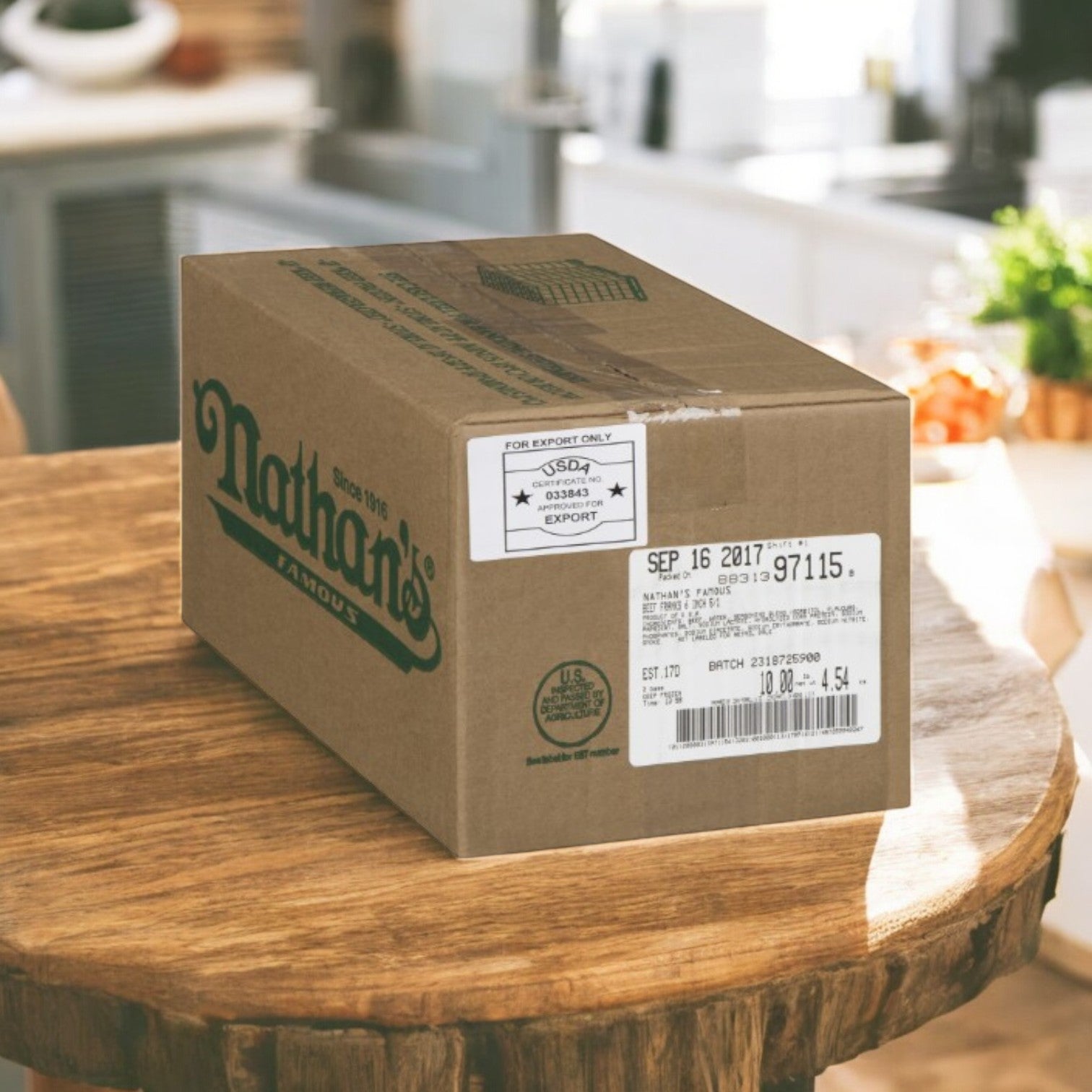 A Nathan's Famous cardboard box containing Nathan's Frankfurter All-beef, 6"-50 Franks A Case, sits on a round wooden table in a kitchen setting, ready to bring the delicious taste of grilling indoors.