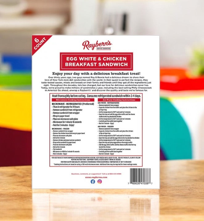 Back of Raybern's Egg White and Chicken Breakfast Sandwich- 1 Pack box displaying heating instructions, nutritional info, and branding against a blurred colorful background.