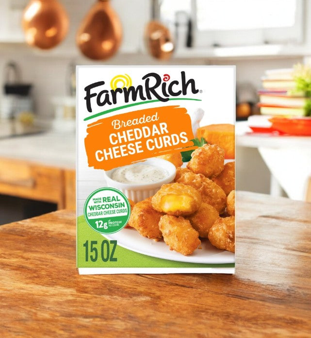 A 15 oz pack of Farm Rich Breaded Wisconsin Cheddar Cheese Curds rests invitingly on a wooden kitchen counter with a softly blurred background, promising the perfect snack with its delicious breaded goodness.