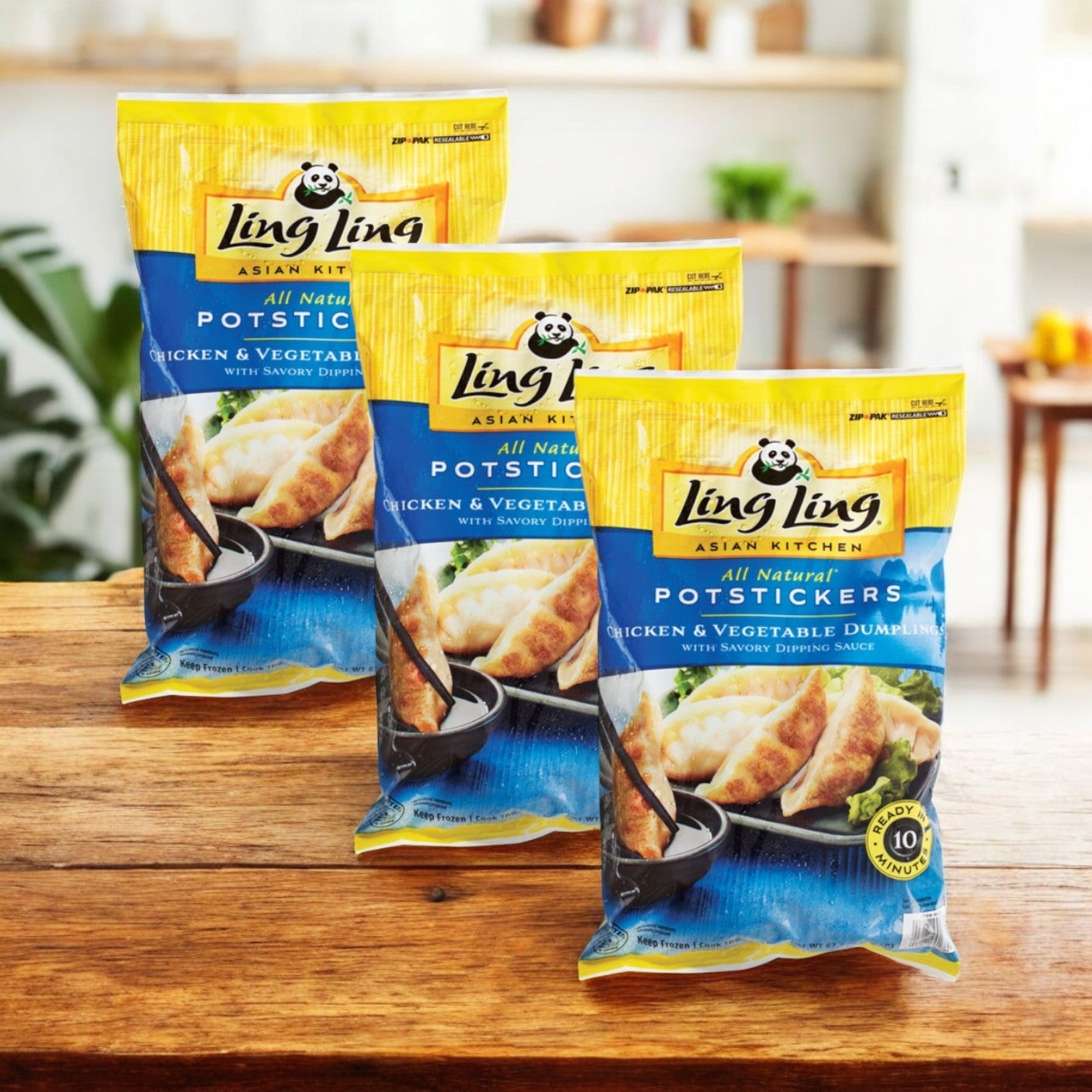 Three packs of Ling Ling Potstickers, All Natural, Chicken & Vegetable (4.2 lbs), are displayed on a wooden surface in a kitchen.