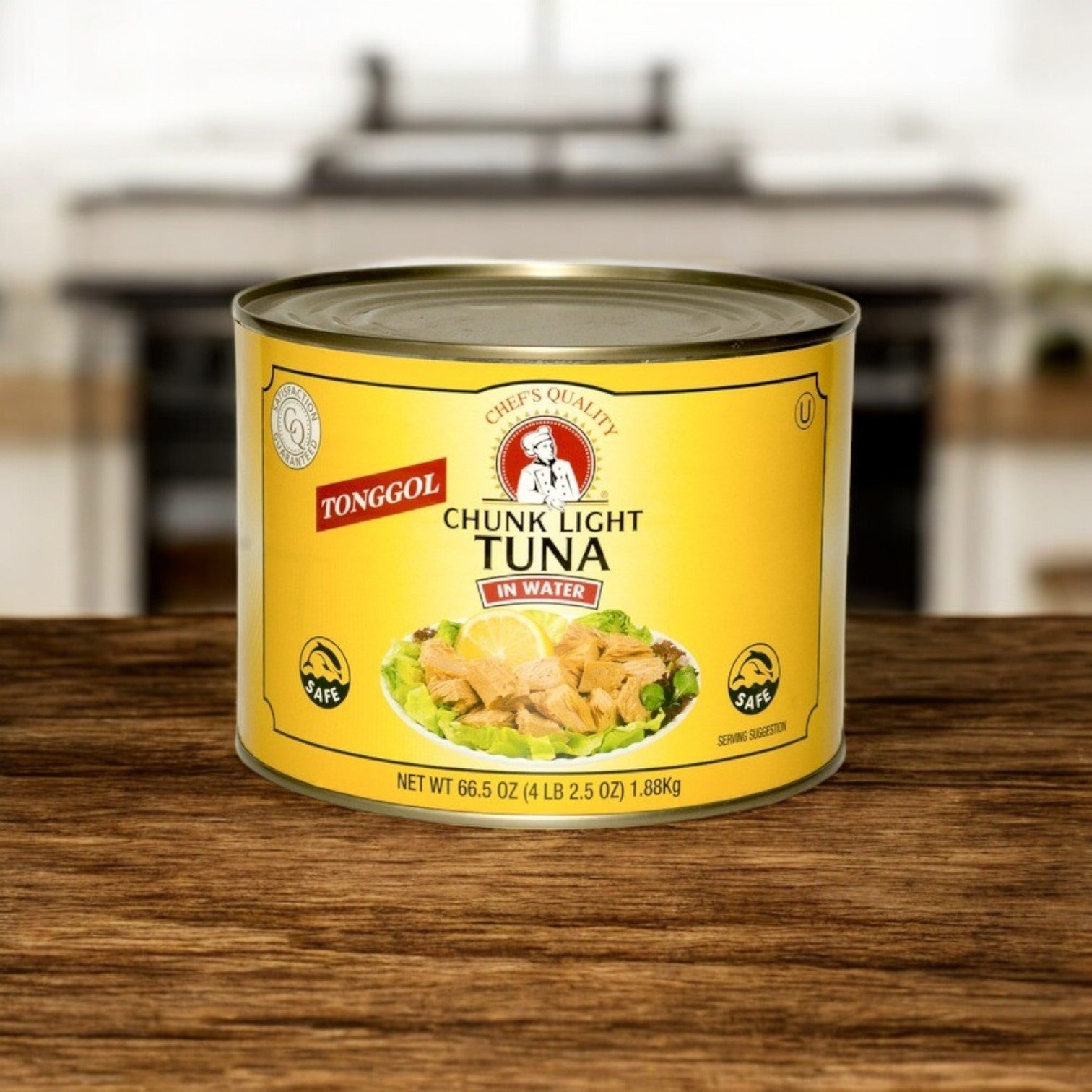A 66.5 oz can of Chef's Quality Tongol Chunk Light Tuna in water sits on a wooden countertop, ideal for foodservice, with a blurred kitchen in the background.