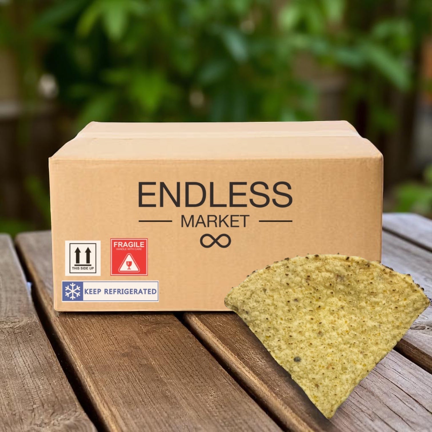 An "El Milagro" box of El Milagro Tortilla Corn 4-way Precut Homestyle 20 LB sits on a wooden surface outdoors, with a single tortilla chip nearby. Ships Mondays—please plan accordingly!.