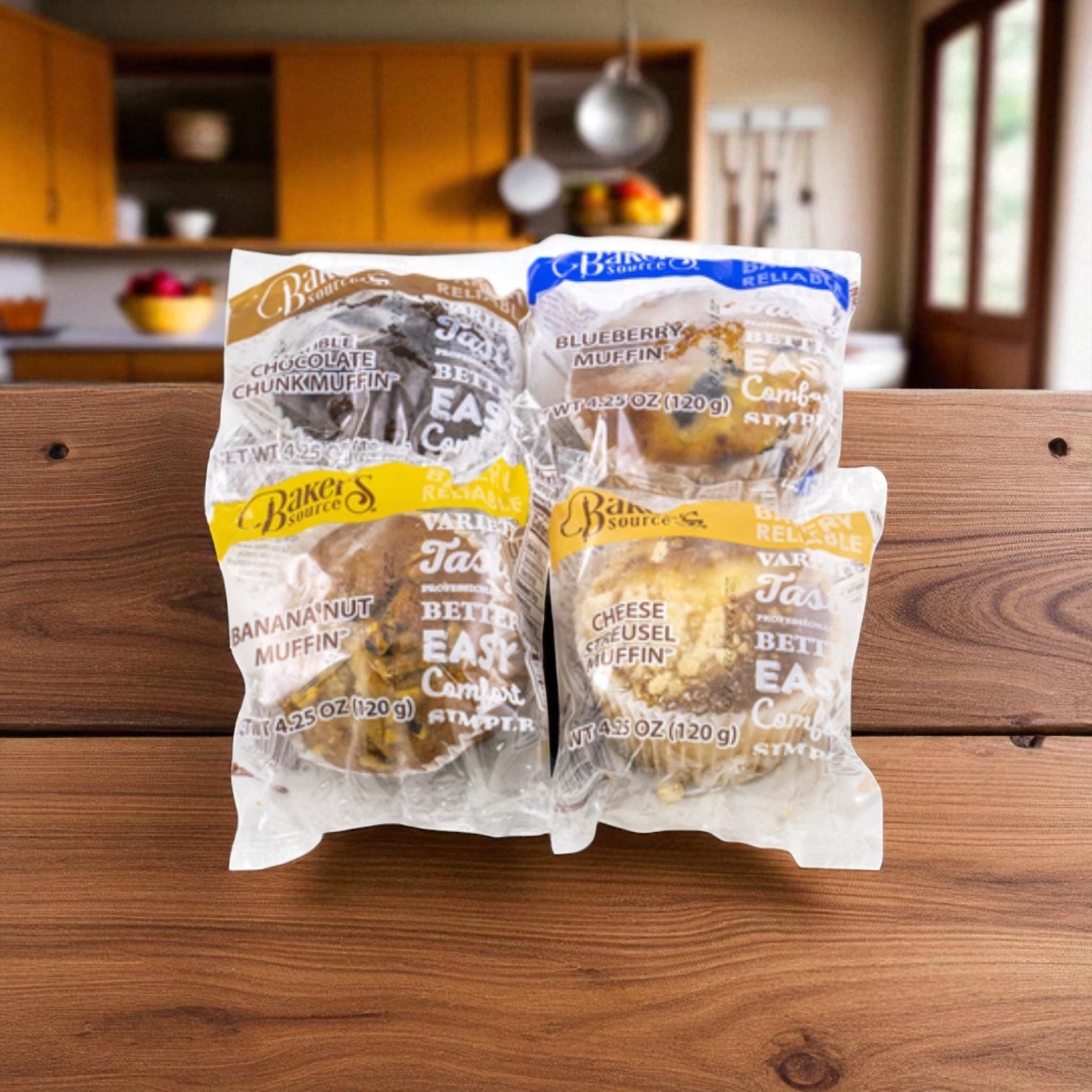 Baker's Source Classic Muffin Assorted Individually Wrapped 4.25 oz - 24 Count offers chocolate chunk, blueberry, banana nut, and cheese muffins—ideal for foodservice or bulk needs, displayed on a kitchen's wooden surface.