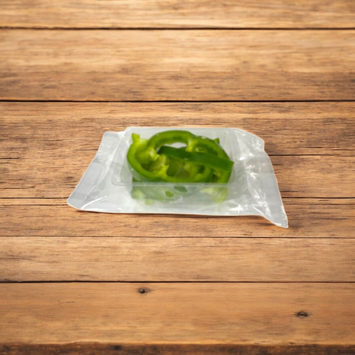 Easy Lunches' Green Pepper Julienne, 2.5 oz., sliced and vacuum-sealed, sits on a wooden surface; this made-to-order item offers a crisp texture with a 7-day shelf life upon receipt. Available in packs of 50.