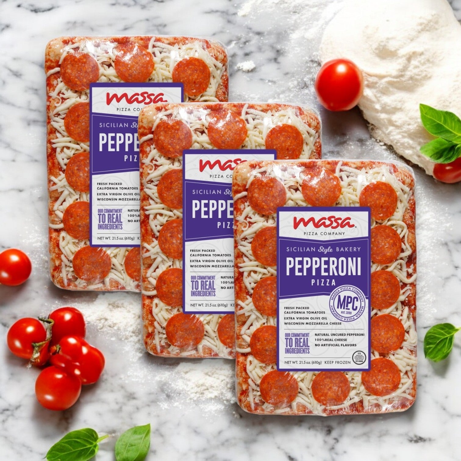 Three boxes of Massa Pizza Company Pepperoni Pizza sit on a marble surface, surrounded by flour, tomatoes, and basil leaves. Made with premium ingredients and a hand-stretched crust, this Sicilian-style pizza offers authentic Italian flavors in every slice.