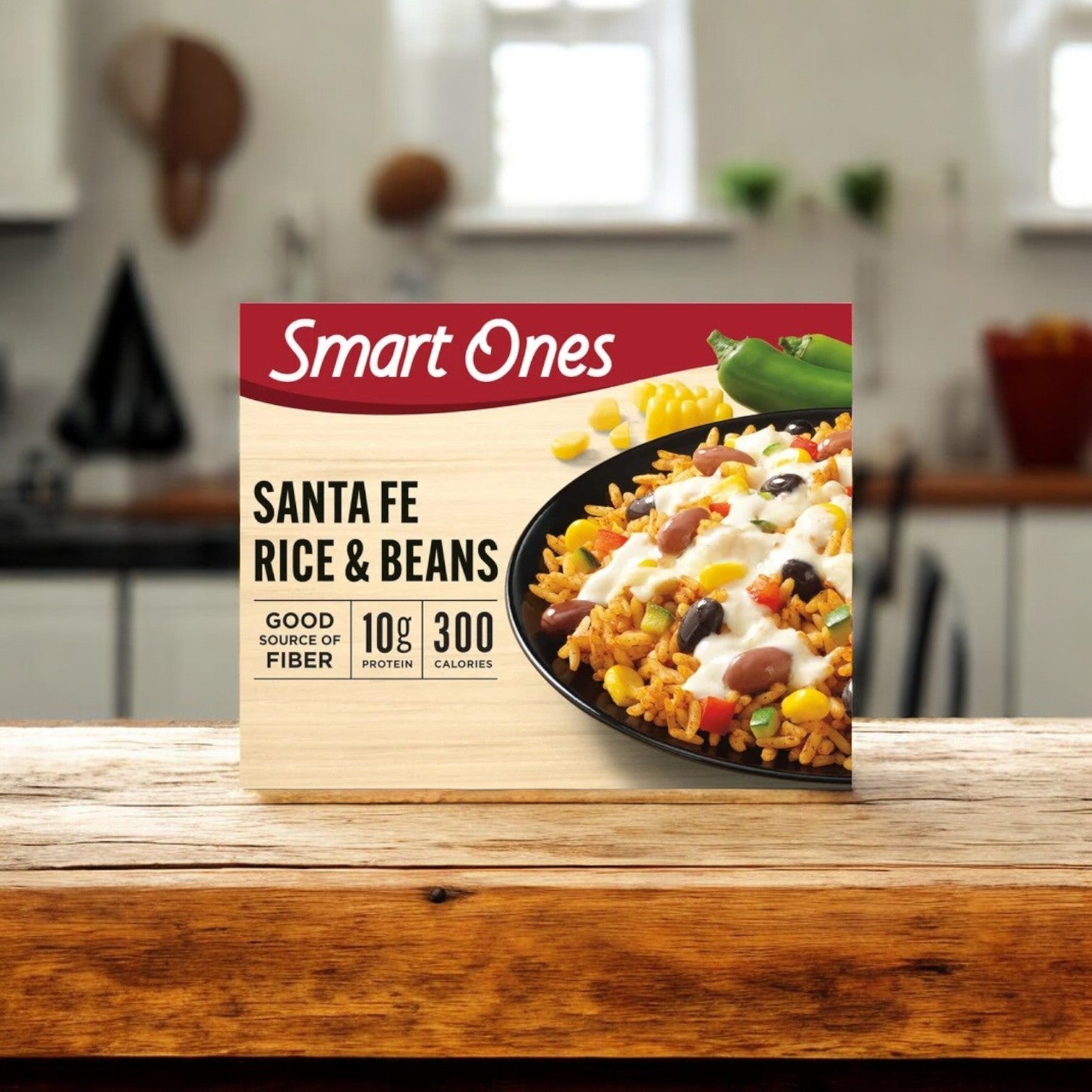 A box of Smart Ones Santa Fe Rice & Beans, 9 oz. - 1 Count, displayed on a wooden counter in a kitchen setting, featuring the quality and flavor you expect from a Smart Ones Frozen Meal.