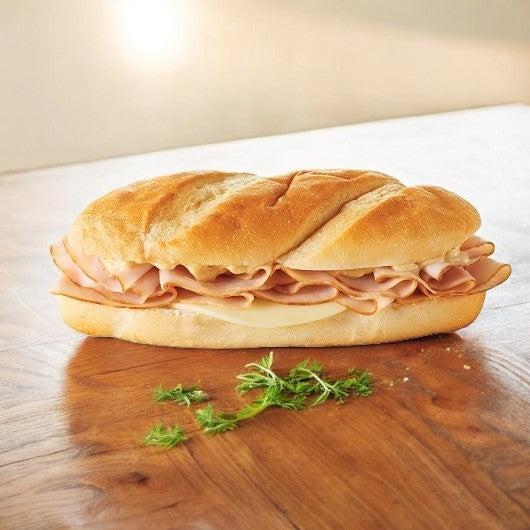 E.A. Sween's Smoked White Turkey & Provolone Cheese Sub lies on a wooden surface, garnished with parsley sprigs.
