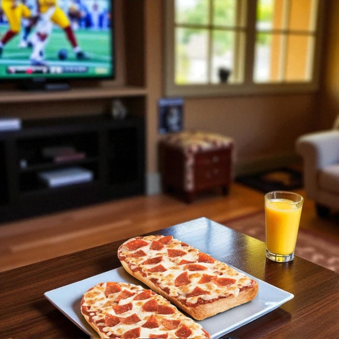 A DRAFT - Stouffer’s Pepperoni French Bread Frozen Pizza from Endless Market sits on a plate next to orange juice, placed on a table in front of a TV showing football in the living room.
