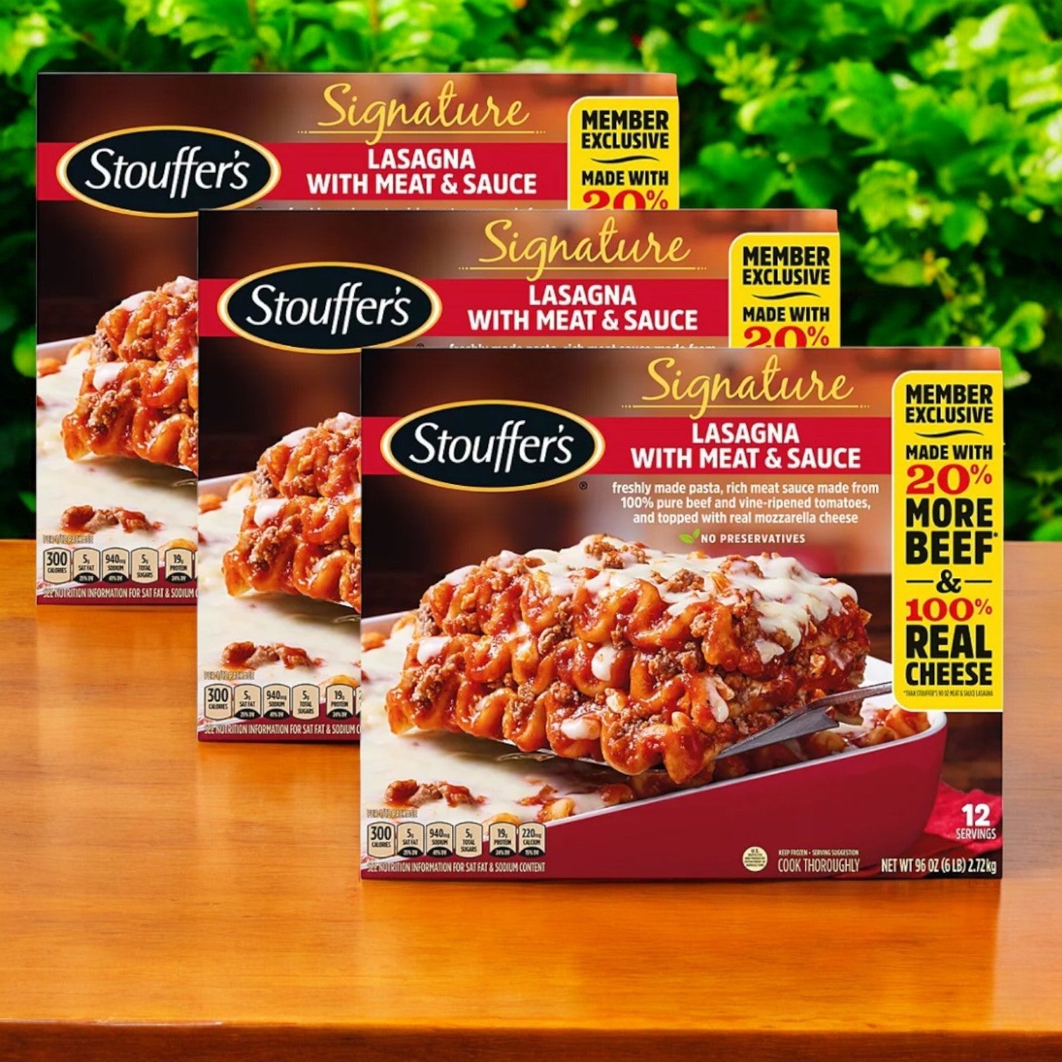 Three boxes of Stouffer's Signature Lasagna with Meat Sauce, each a 96 oz. perfect family meal, are displayed on a wooden surface with greenery in the background.
