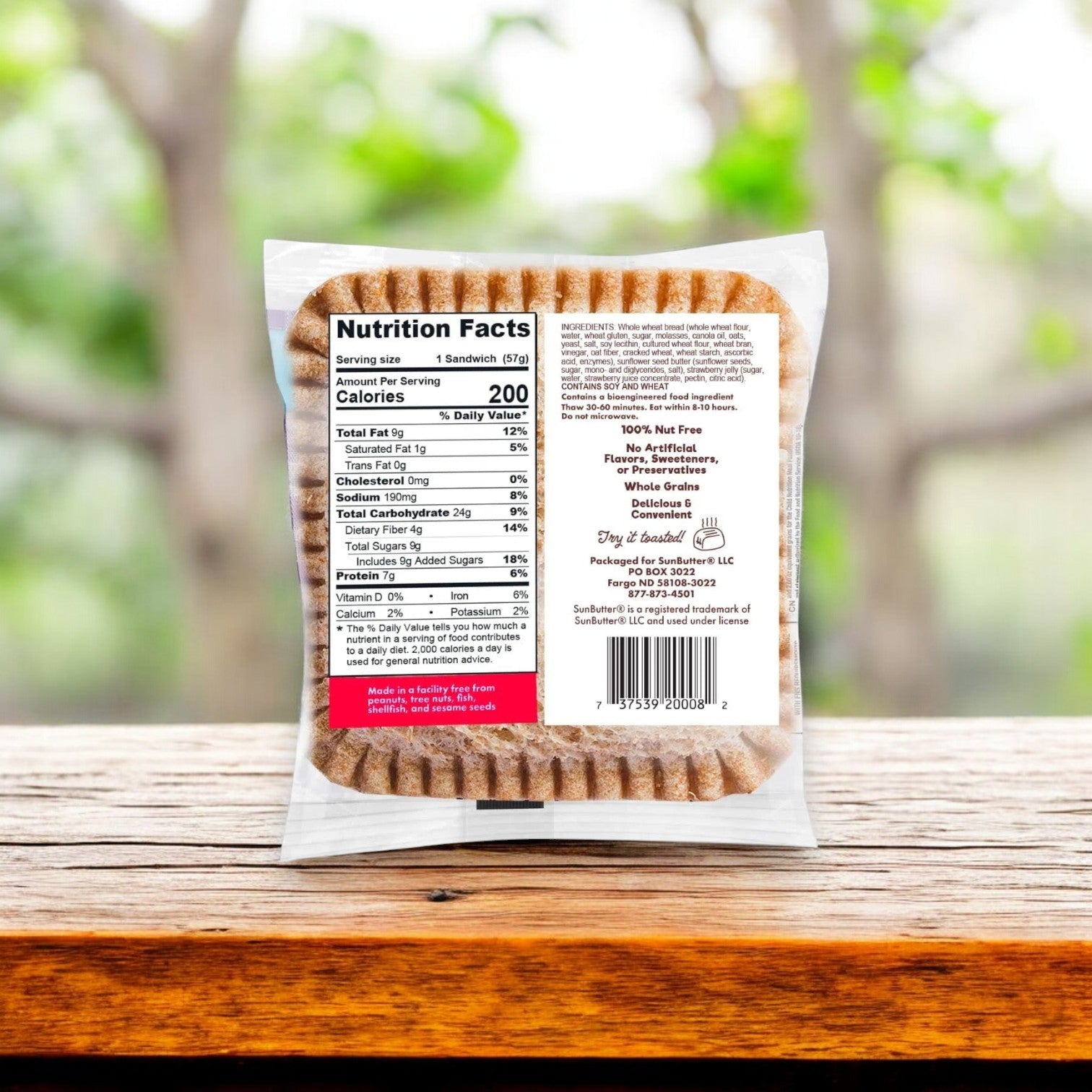 The SunButter Sunflower Butter & Strawberry Jelly Sandwich Jammies, 8 oz. - 4 Count by Sunbutter are showcased on a wooden table with clear nutrition facts, highlighting their nut-free convenience against a softly blurred green background.