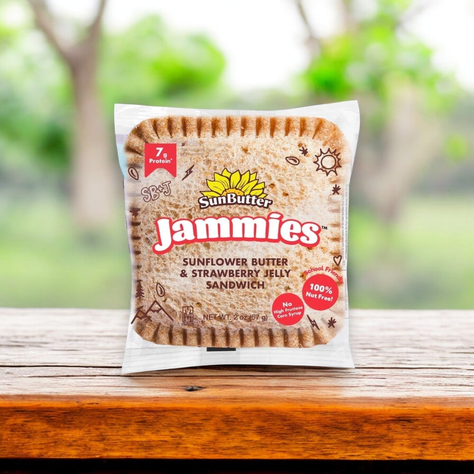 A SunButter Sunflower Butter & Strawberry Jelly Sandwich Jammie from the 8 oz. - 4 Count pack rests on a wooden surface, featuring nut-free sunflower butter and strawberry jelly, with a blurred outdoor background.