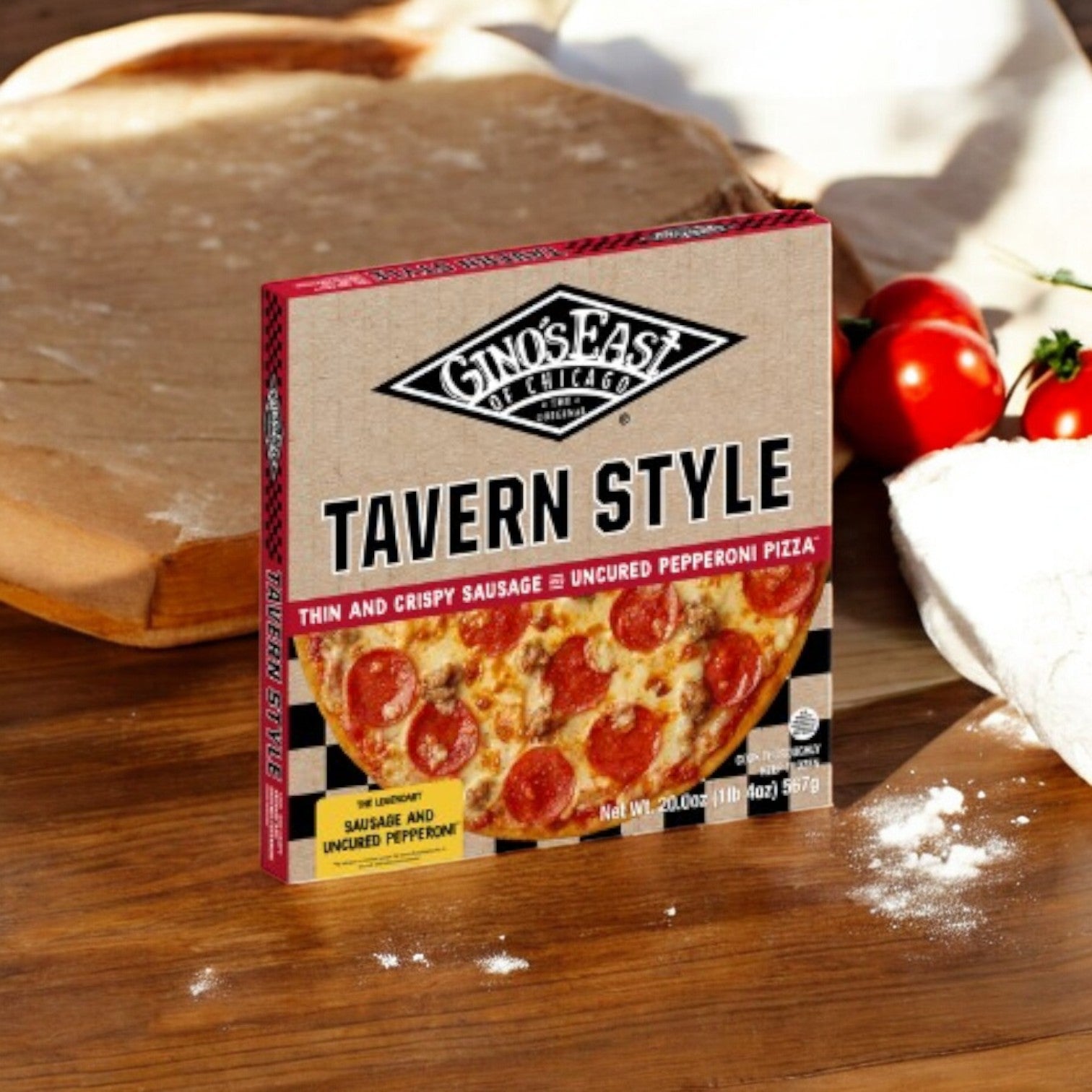 A box of Gino's East Tavern Style Combo 4 Pack! from Gino's East Pizza sits on a wooden surface surrounded by fresh tomatoes, dough, and flour.