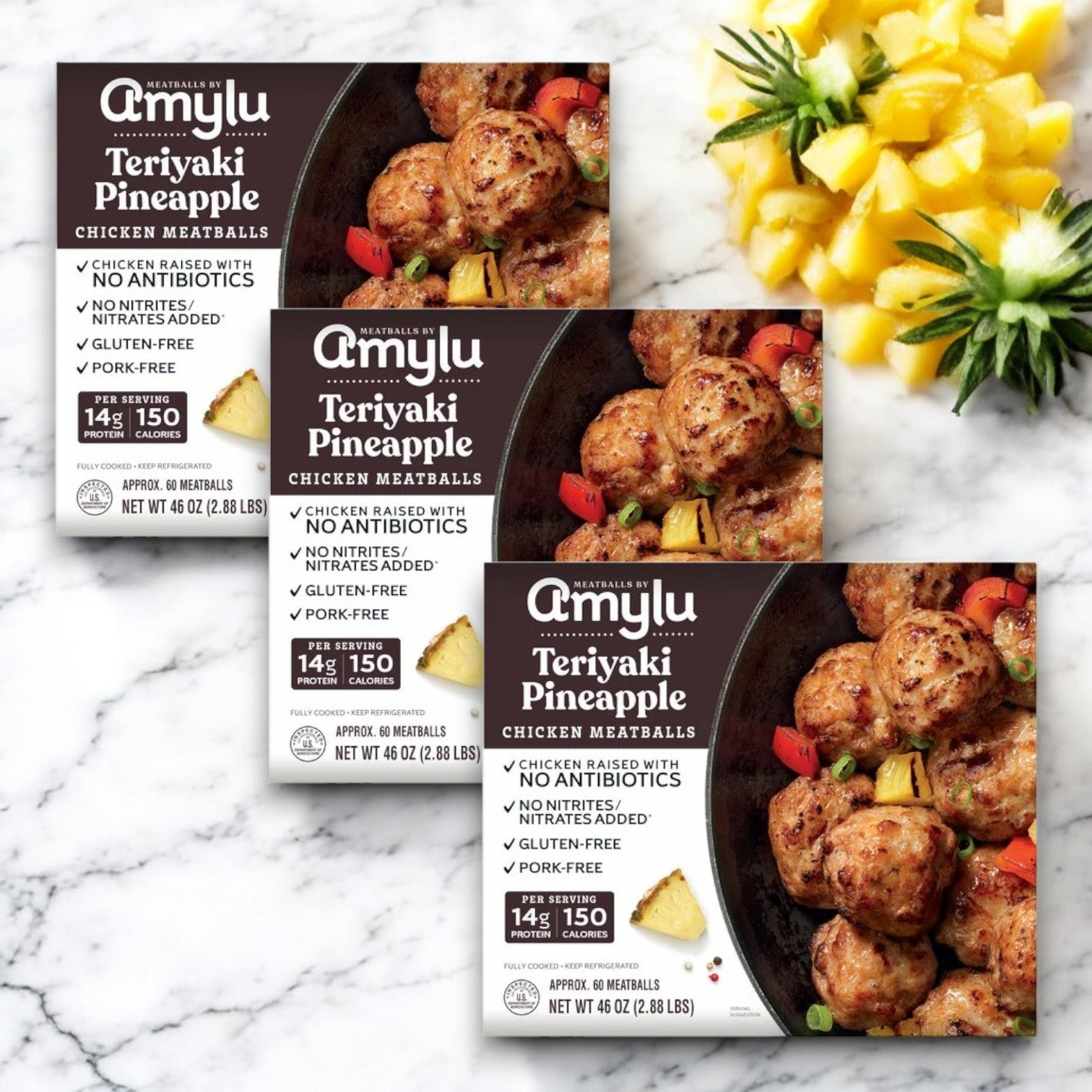 Packages of Amylu Teriyaki Pineapple Chicken Meatballs (46 oz - 3 Packs) are shown with pineapple chunks. The packaging features highlights like juicy teriyaki glaze, antibiotic-free chicken, gluten-free, and pork-free.