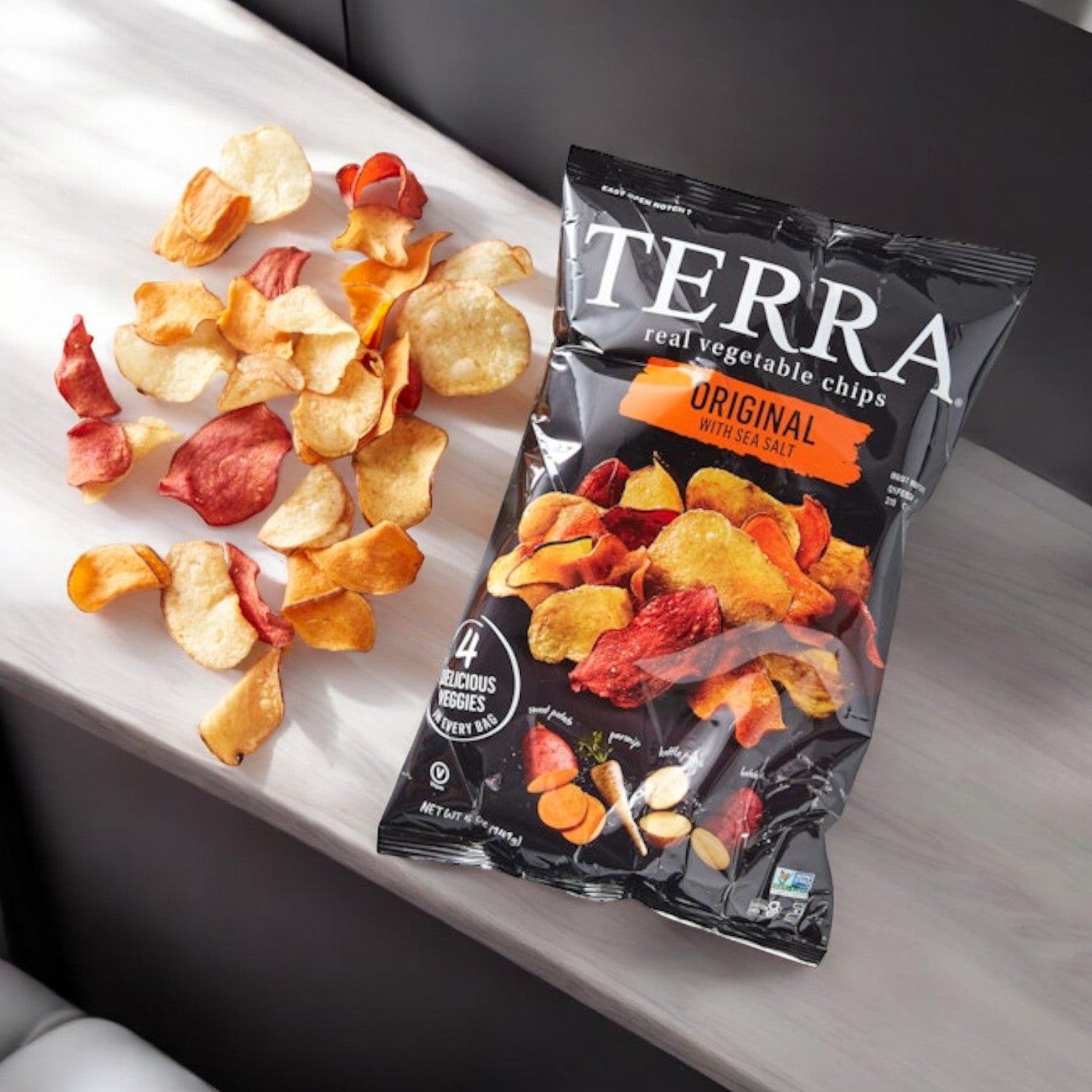 A bag of Terra Original Chips, 5 oz., from Terra lies open with a few chips scattered. The packaging emphasizes sea salt and a vibrant mix of four root vegetables, ideal for healthy snack seekers.