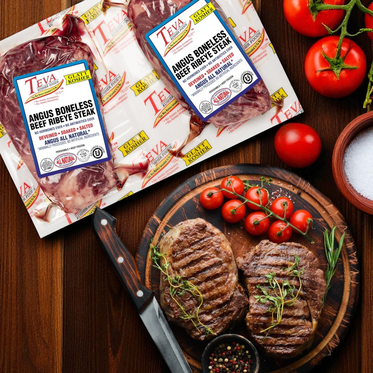 Three 2-count packs of Teva Kosher Foods Glatt Kosher Angus Boneless Ribeye Steaks are shown beside a cutting board with grilled steak, cherry tomatoes, salt, pepper, rosemary, and a knife. Serve top-quality kosher ribeye at your next meal.