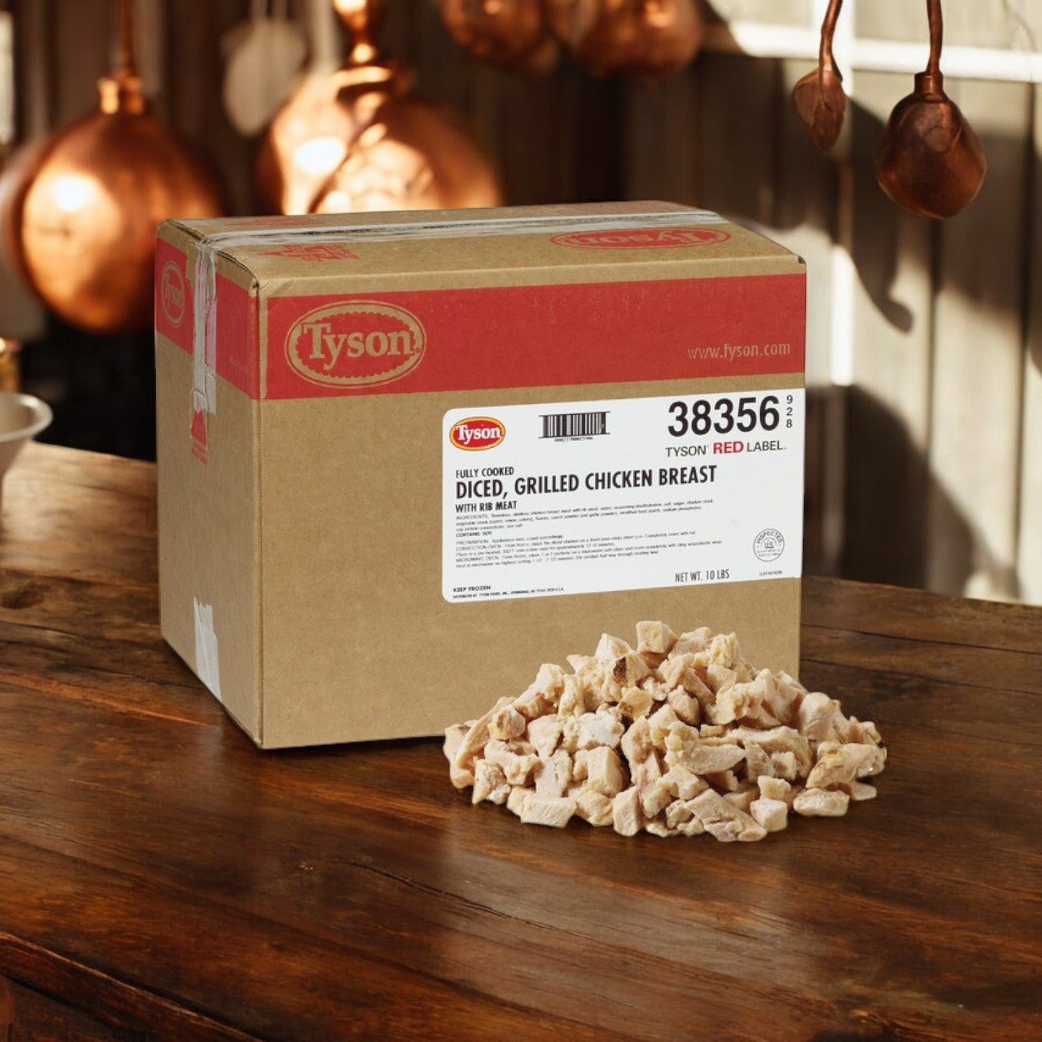 A box of Tyson Red Label Diced Chicken Breast, 10 lbs, is on a wooden surface with a pile of all-natural chicken beside it. Elegant copper pots hang in the background, adding a rustic touch.