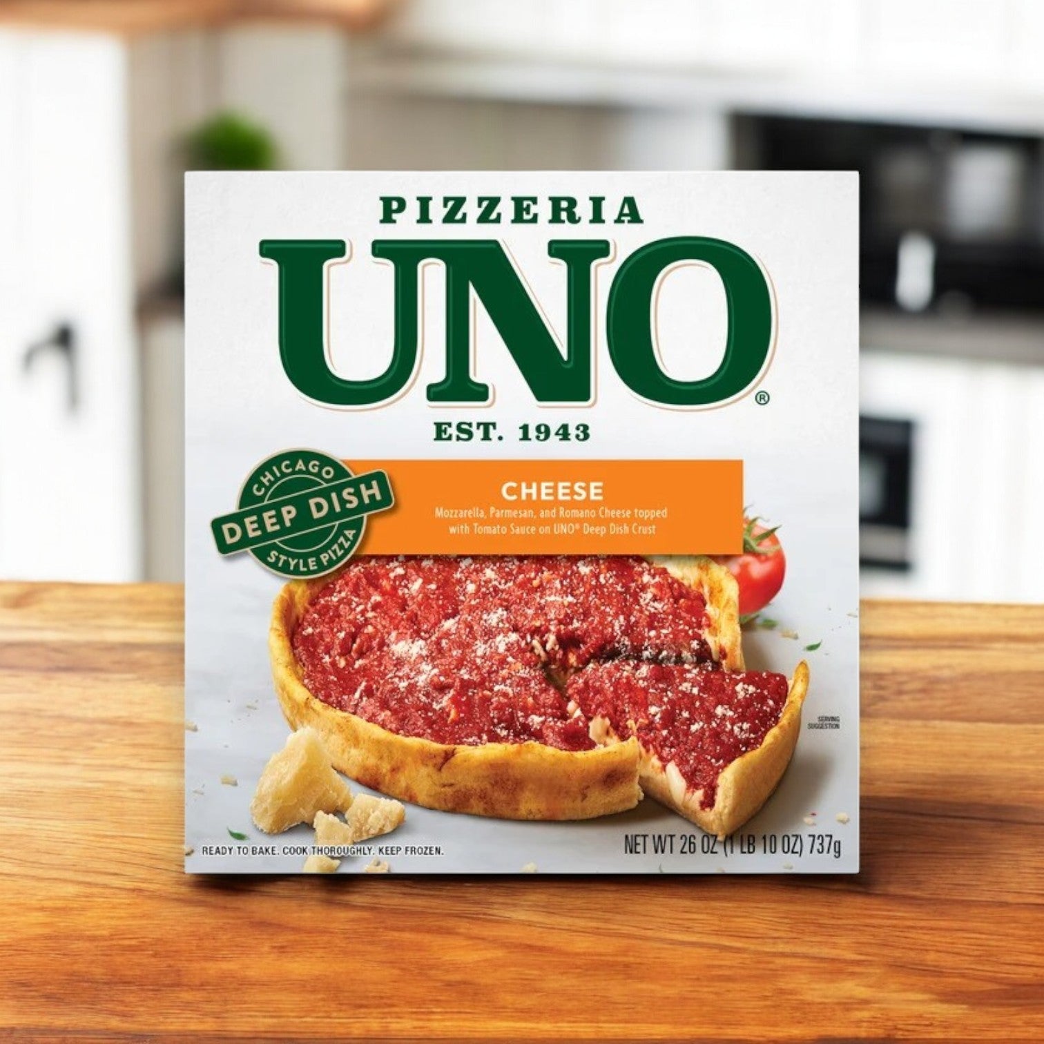 A box of Uno Chicago Style Deep Dish Cheese Pizza, 26 oz., by Pizzeria Uno rests on a wooden surface with its irresistible buttery crust and gooey mozzarella, set against a kitchen backdrop.