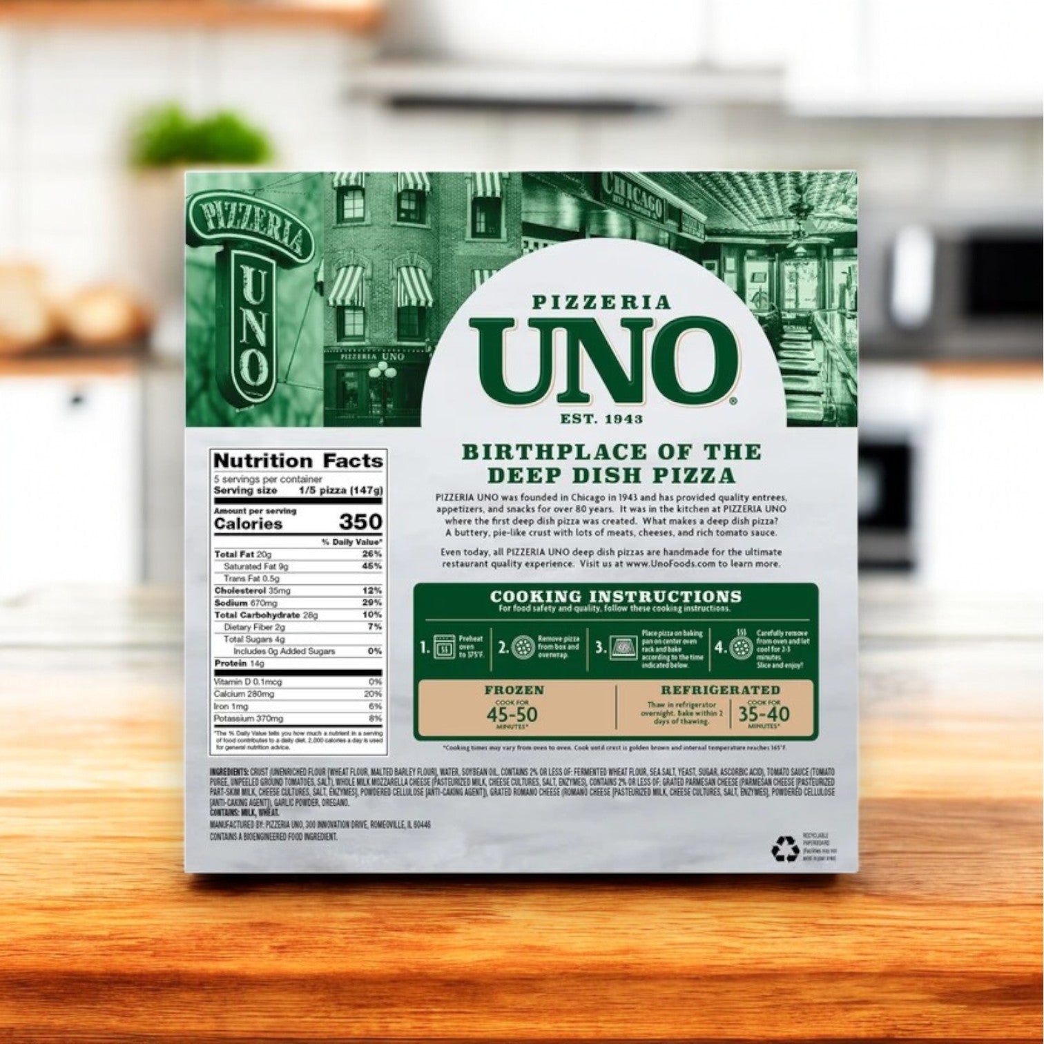 The back of a Pizzeria Uno Uno Chicago Style Deep Dish Cheese Pizza, 26 oz. box sits on the kitchen counter, featuring nutritional facts, cooking instructions, and praising its buttery crust and rich mozzarella as the essence of authentic Chicago-style deep dish pizza from its birthplace.