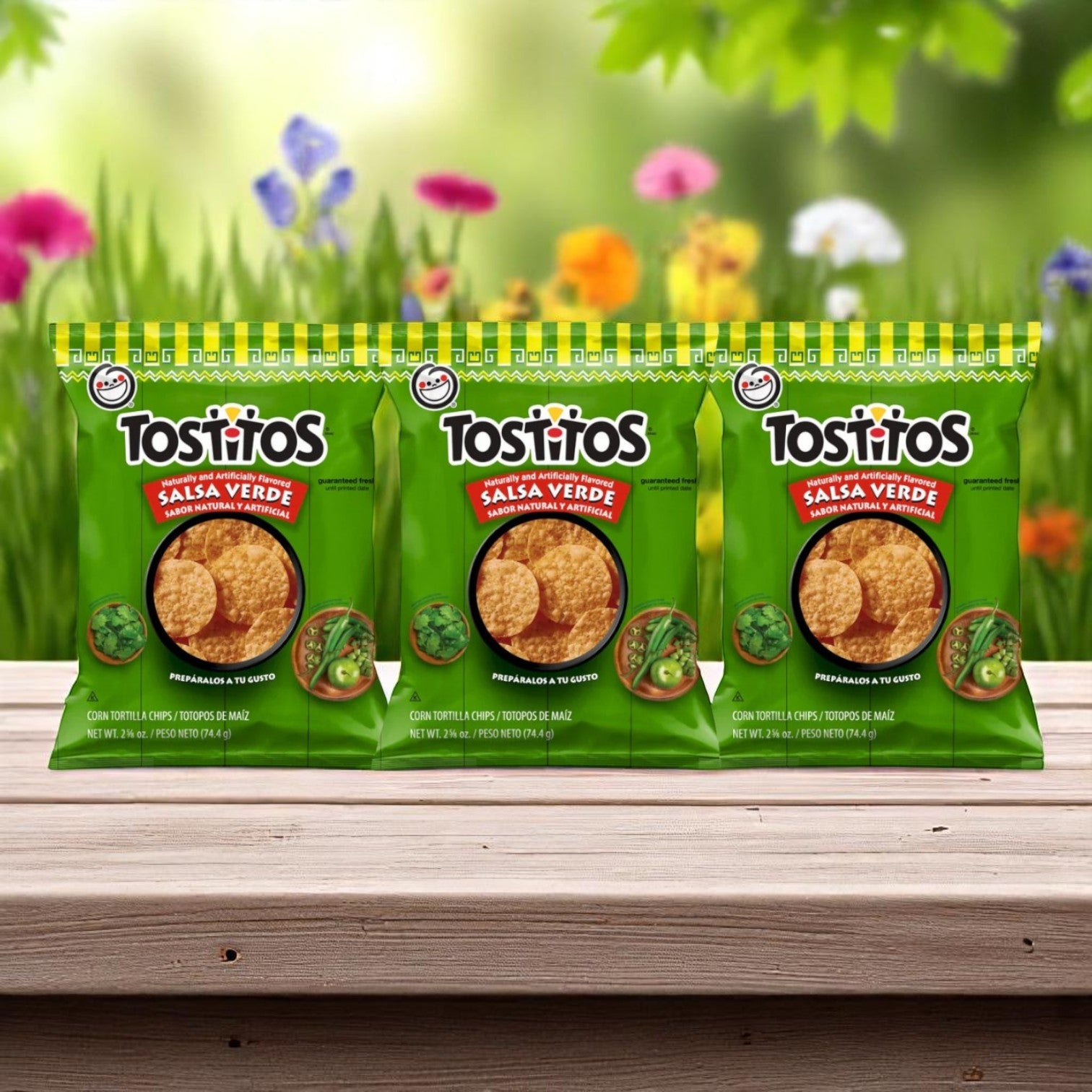 Three E.A. Sween 10-Pack Wrap & Sub Sandwich Bundles with 10 assorted snack chips are displayed on a wooden surface, backed by blurred green grass and colorful flowers outdoors.