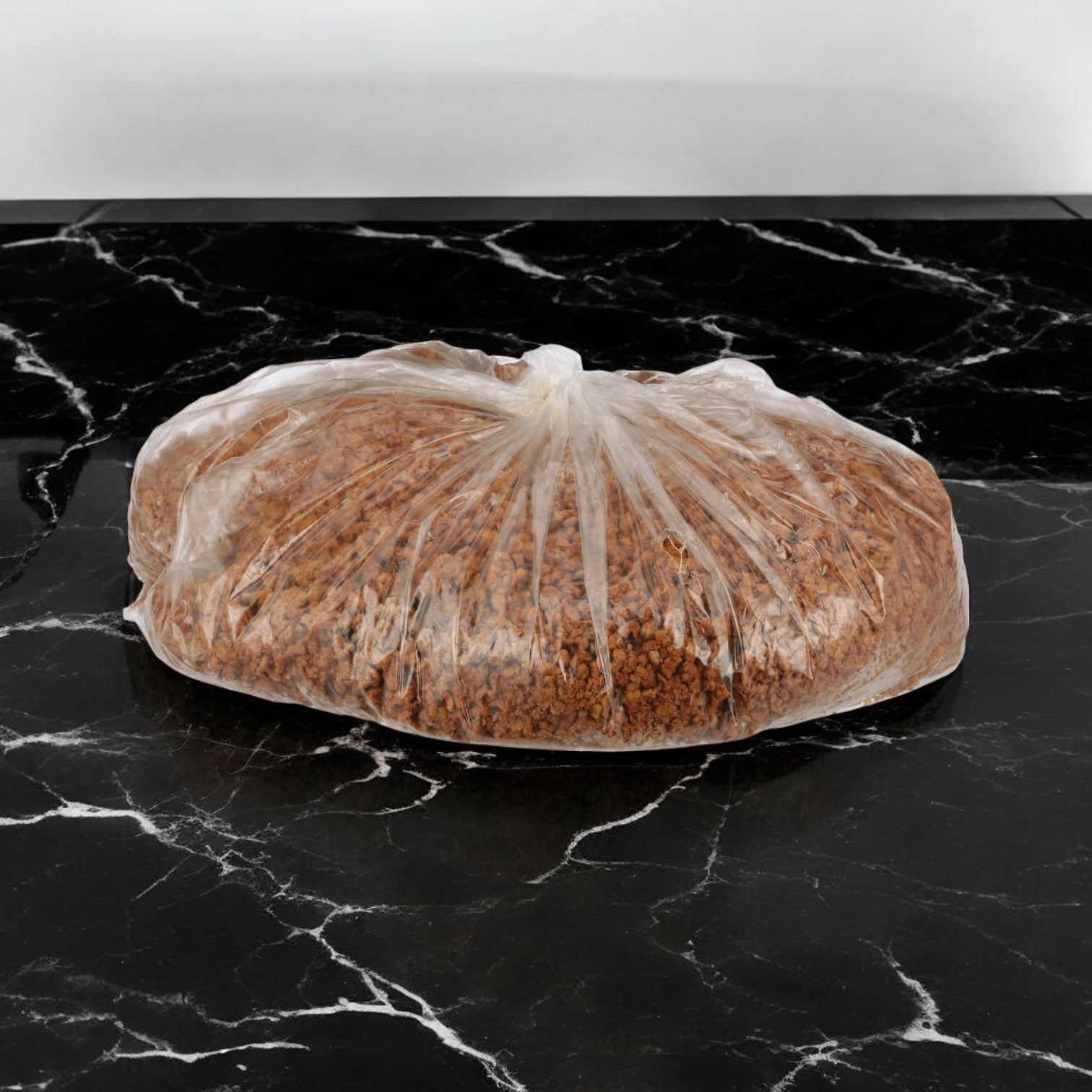 A Gardein Veggie Burger Vegetarian Soy Ground Crumble Gluten-free bag is set on a sleek black marble surface, featuring brown granules that resemble vegetarian soy ground crumble.