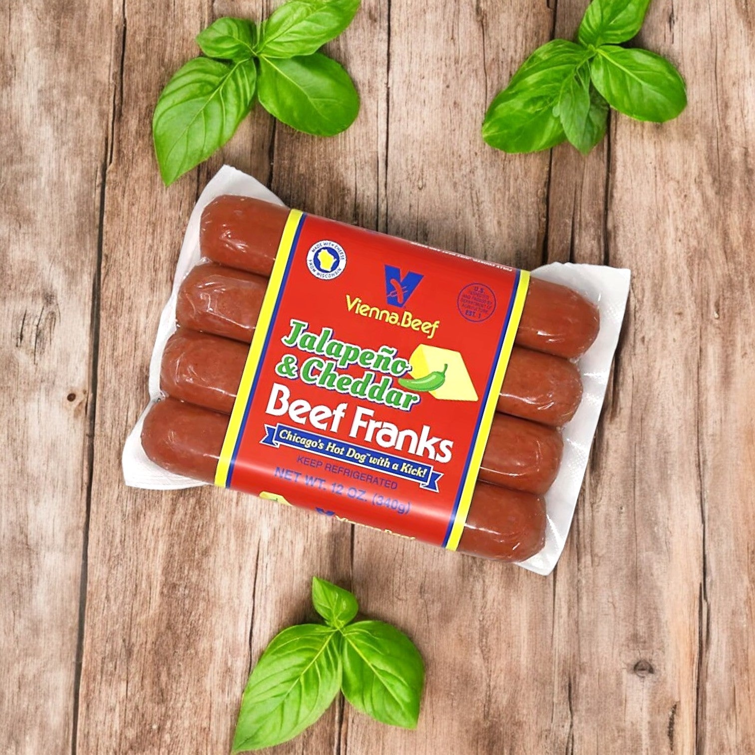 A package of Vienna Beef Variety Pack – A Classic Selection of Chicago’s Finest Sausages! rests on a wooden surface, surrounded by fresh basil leaves.