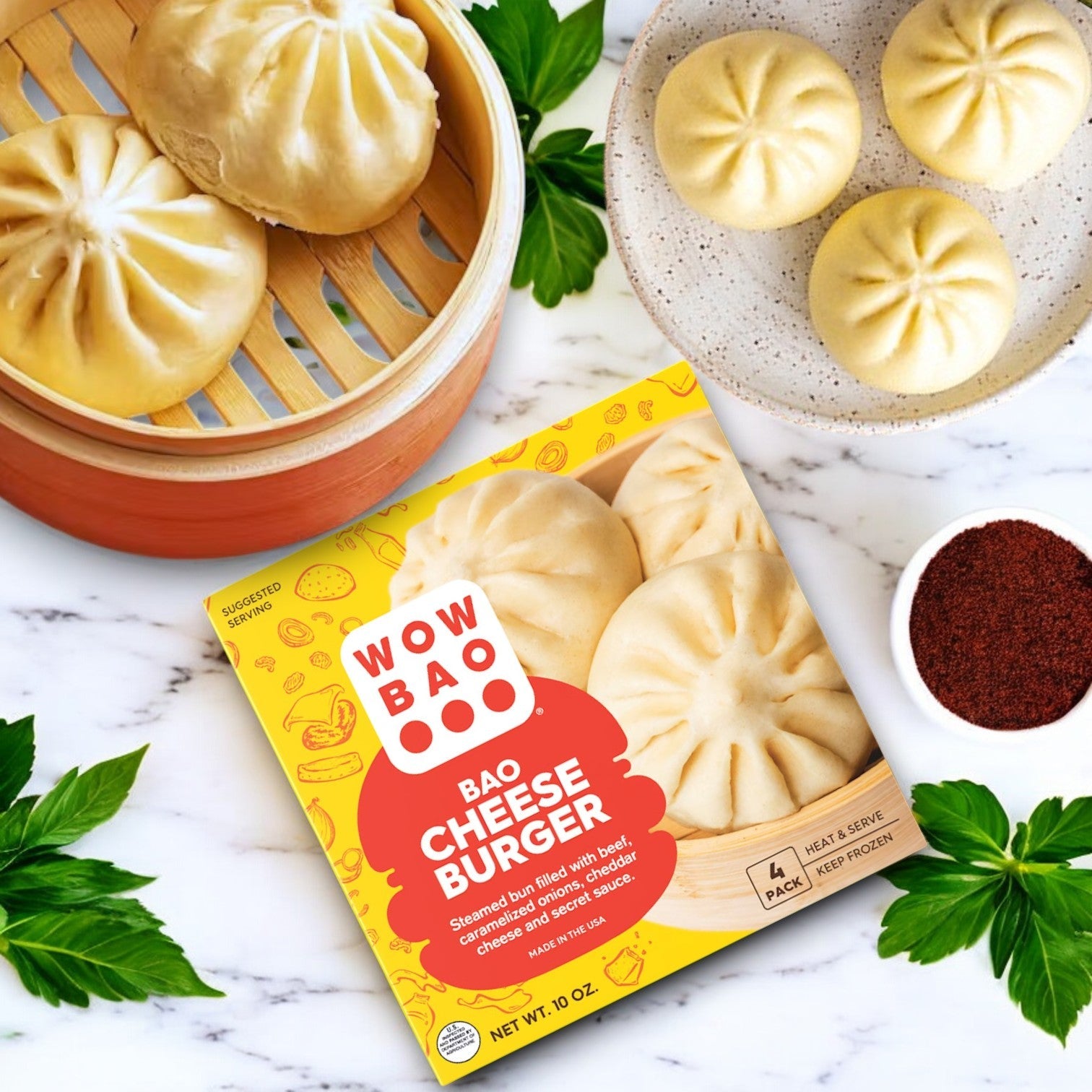 The Wow Bao 3 Pack Combo! features bao buns on a marble surface with cilantro leaves and red spice. Enjoy this delightful twist on the classic cheeseburger, where each bite from the brand Wow Bao tantalizes your taste buds.