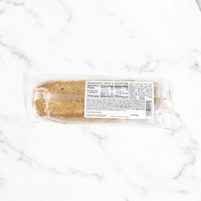 The E.A. Sween Smoked Turkey & Cheddar Sub Sandwich, wrapped in clear packaging with a detailed white label, is placed on a marble surface.