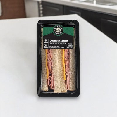 A Smoked Ham & Cheese Sandwich Wedge from E.A. Sween, complete with a nutrition label, rests on a white kitchen countertop. This ready-to-eat sandwich is frozen and remains fresh for 30 days once out of the freezer and stored in the cooler.